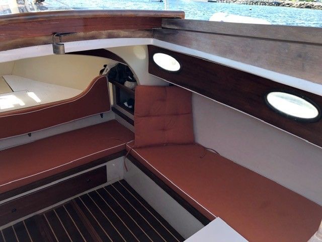 Interior view of a 1973 Talman Yacht Menemsha-24 with red cushions and wood accents.