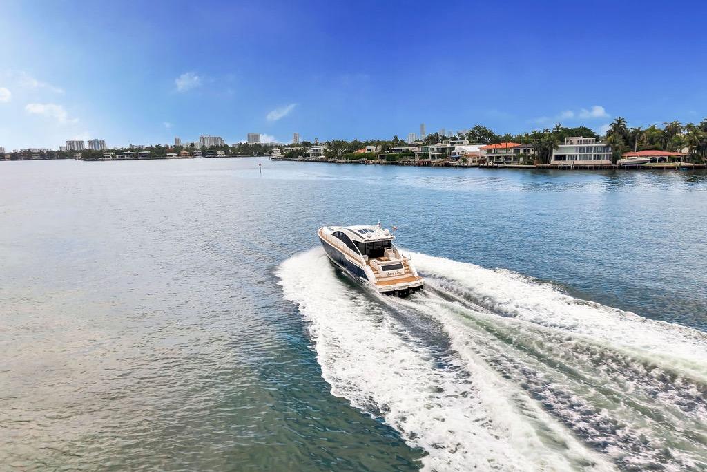 2012 Fairline Targa 58 yacht cruising on a scenic waterway with waterfront homes.
