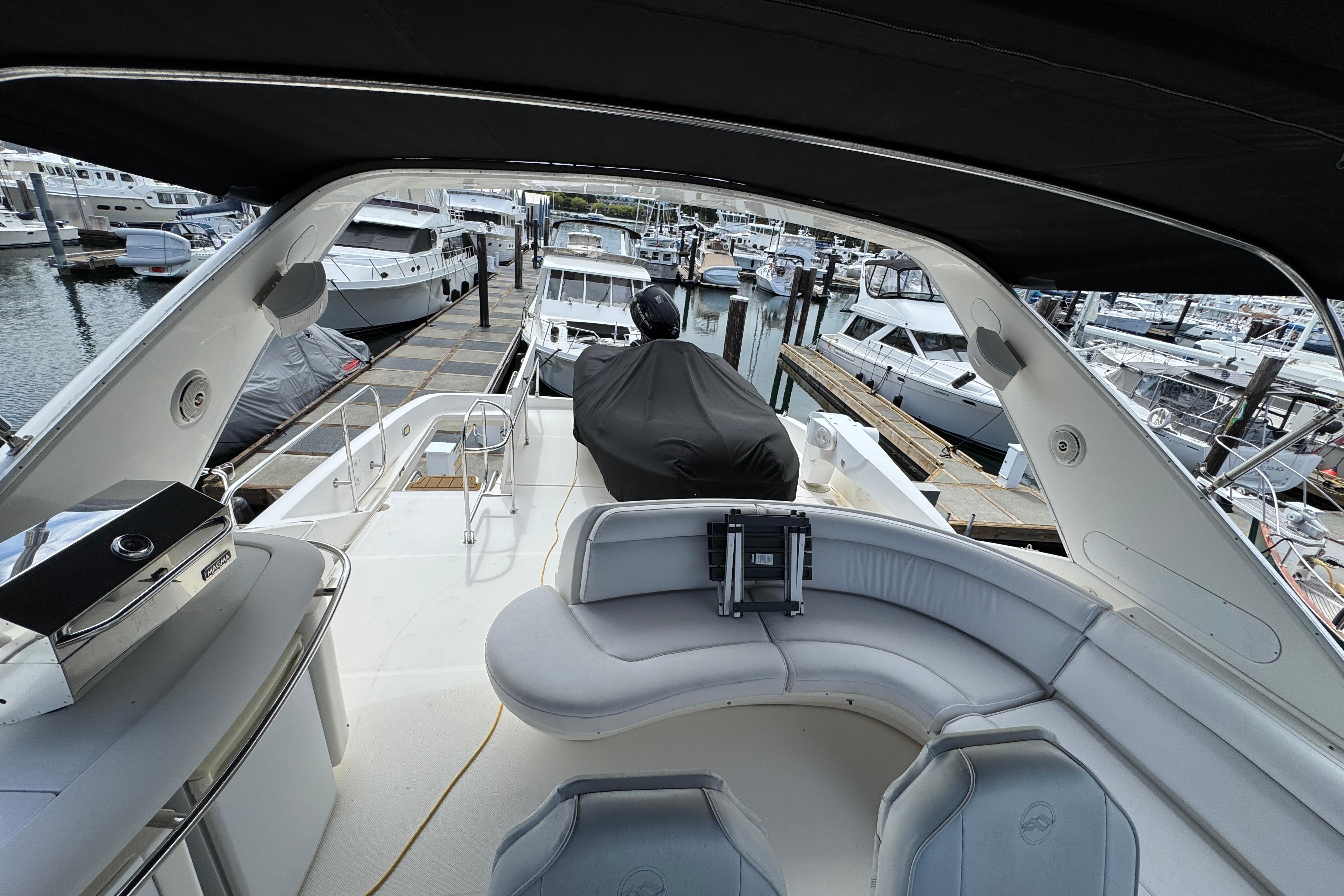 1998 Bayliner 5788 Pilot House Motoryacht interior with marina view, featuring seating and grill.