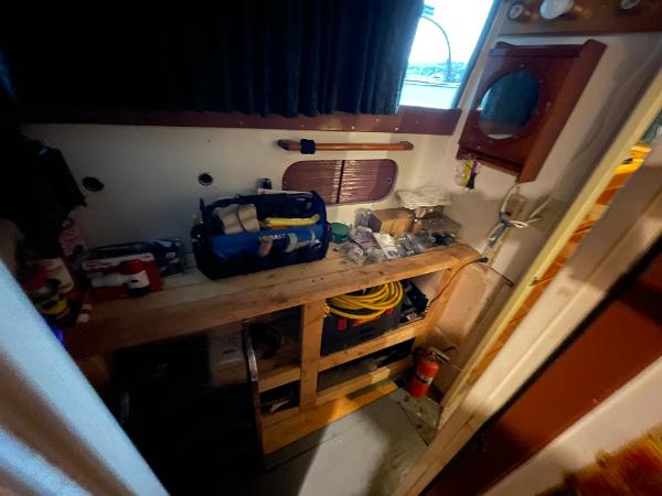Interior of a 1951 Chris-Craft Catalina boat with tools and equipment on a wooden shelf.