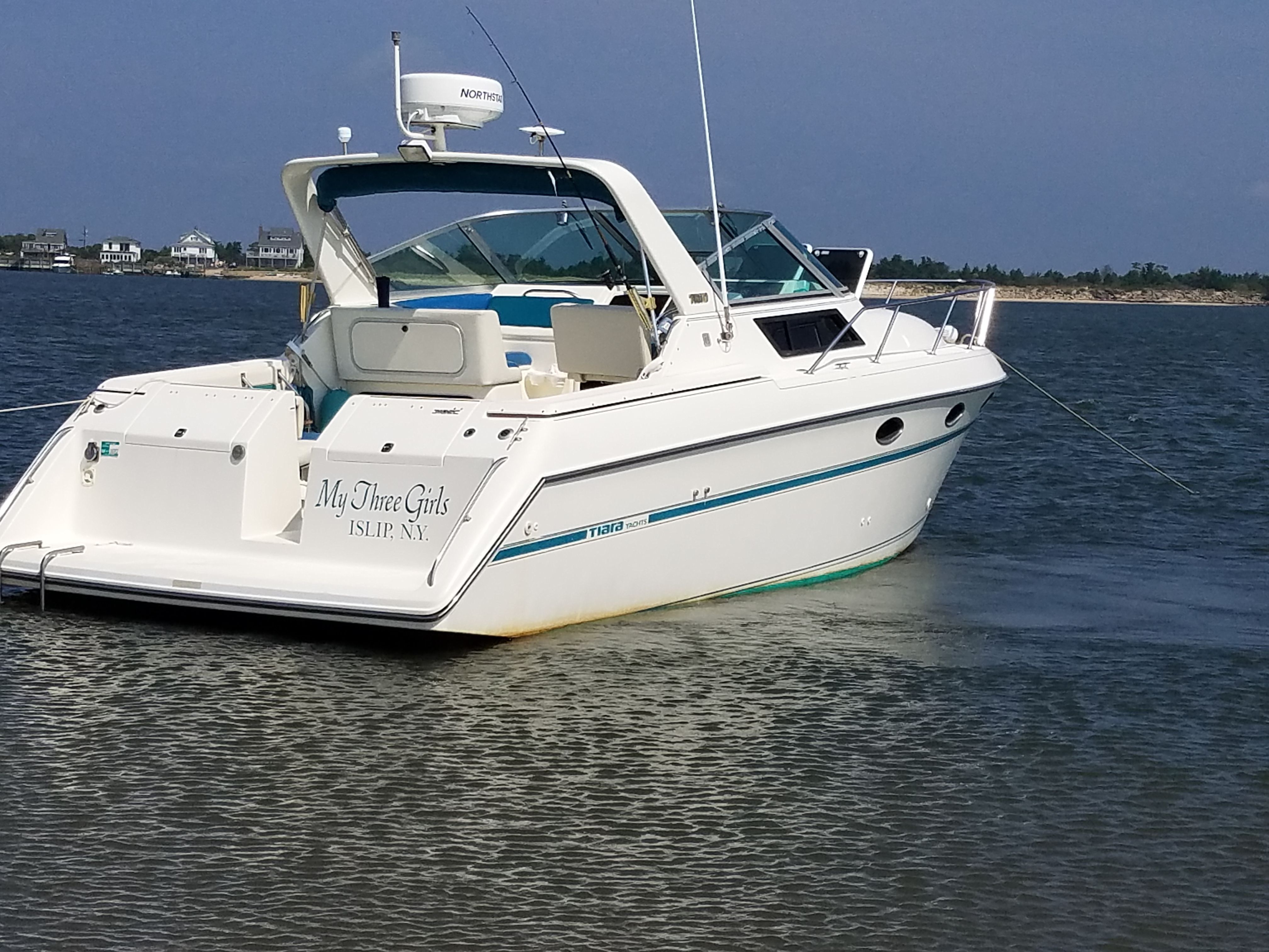 A white motorboat anchored in the water, featuring an open cabin and blue accents.