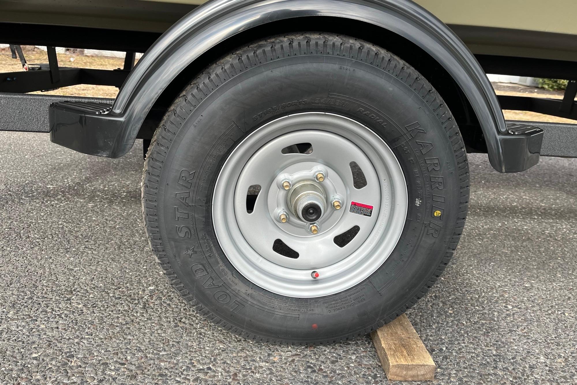 Trailer wheel of 2026 Tracker Grizzly 1754 Utility on a wooden block.