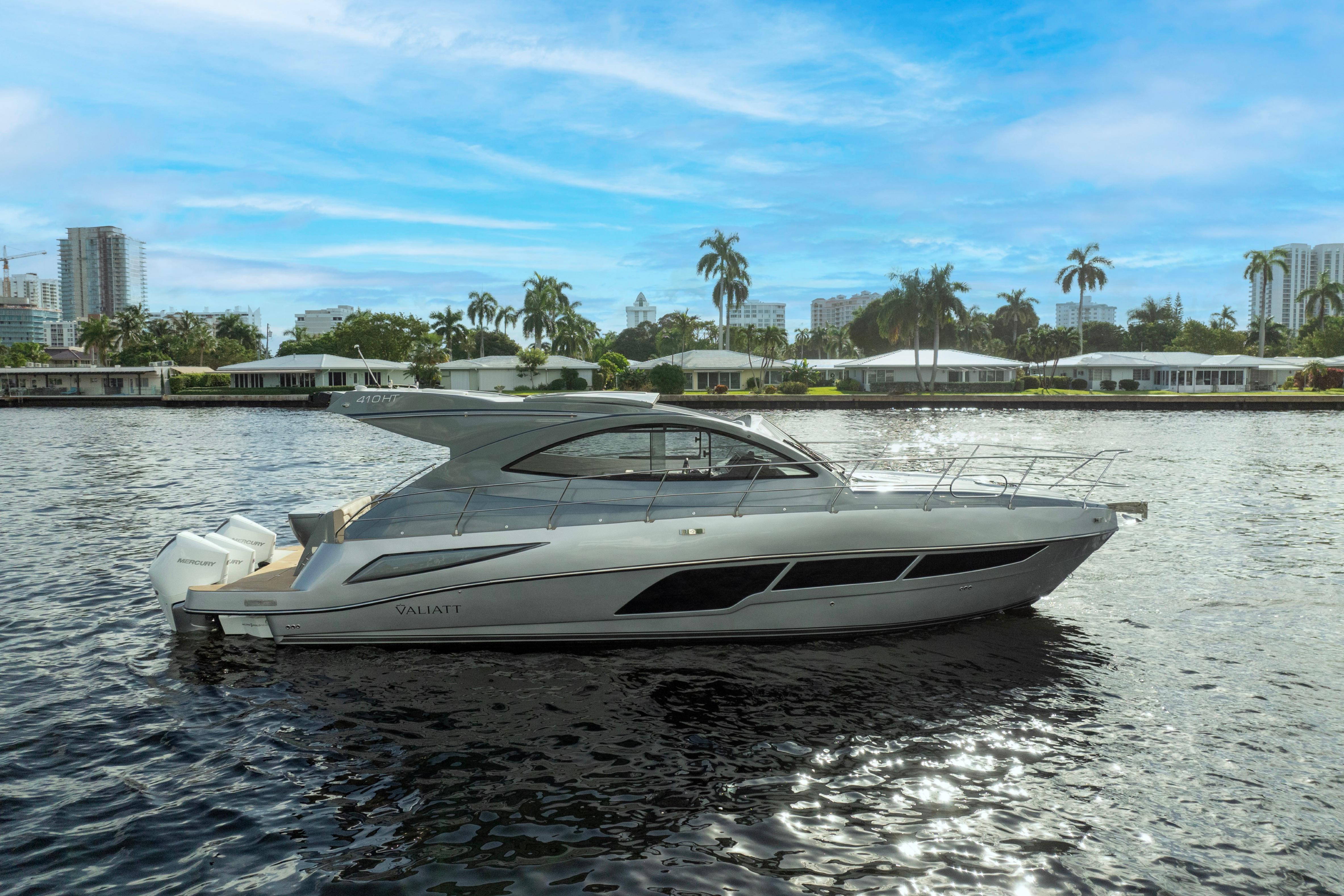 2025 Valiatt 410HT luxury yacht on a scenic waterfront with palm trees and city skyline.
