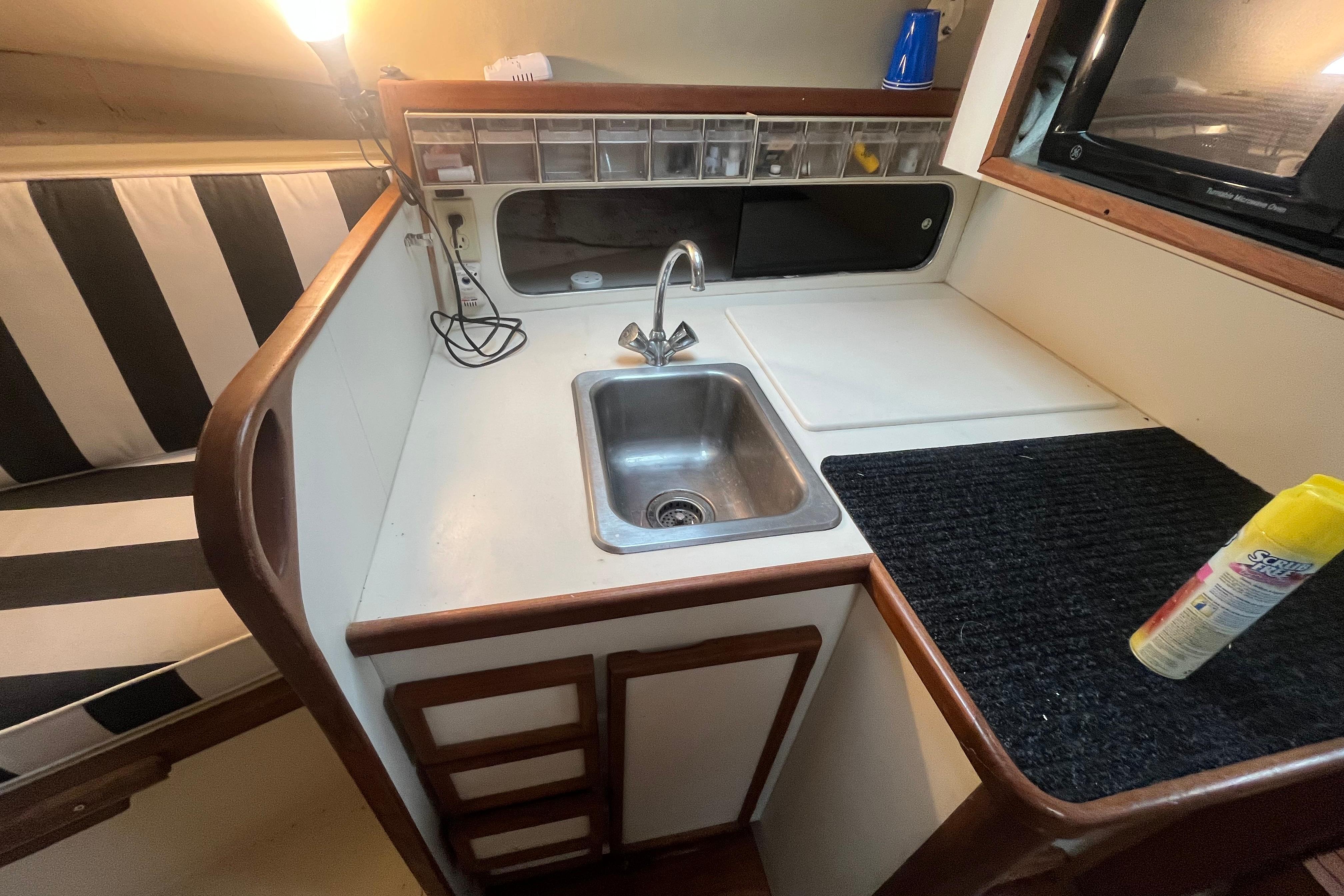 1989 Blackfin 31 Combi boat interior with kitchenette, sink, and striped seating.