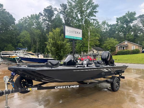 2025 Crestliner XF 179 boat on trailer at dealership, surrounded by trees and other boats.