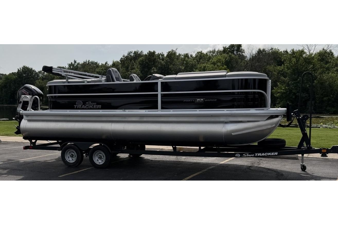 2026 Sun Tracker Party Barge 22 DLX pontoon boat on trailer, parked outdoors.