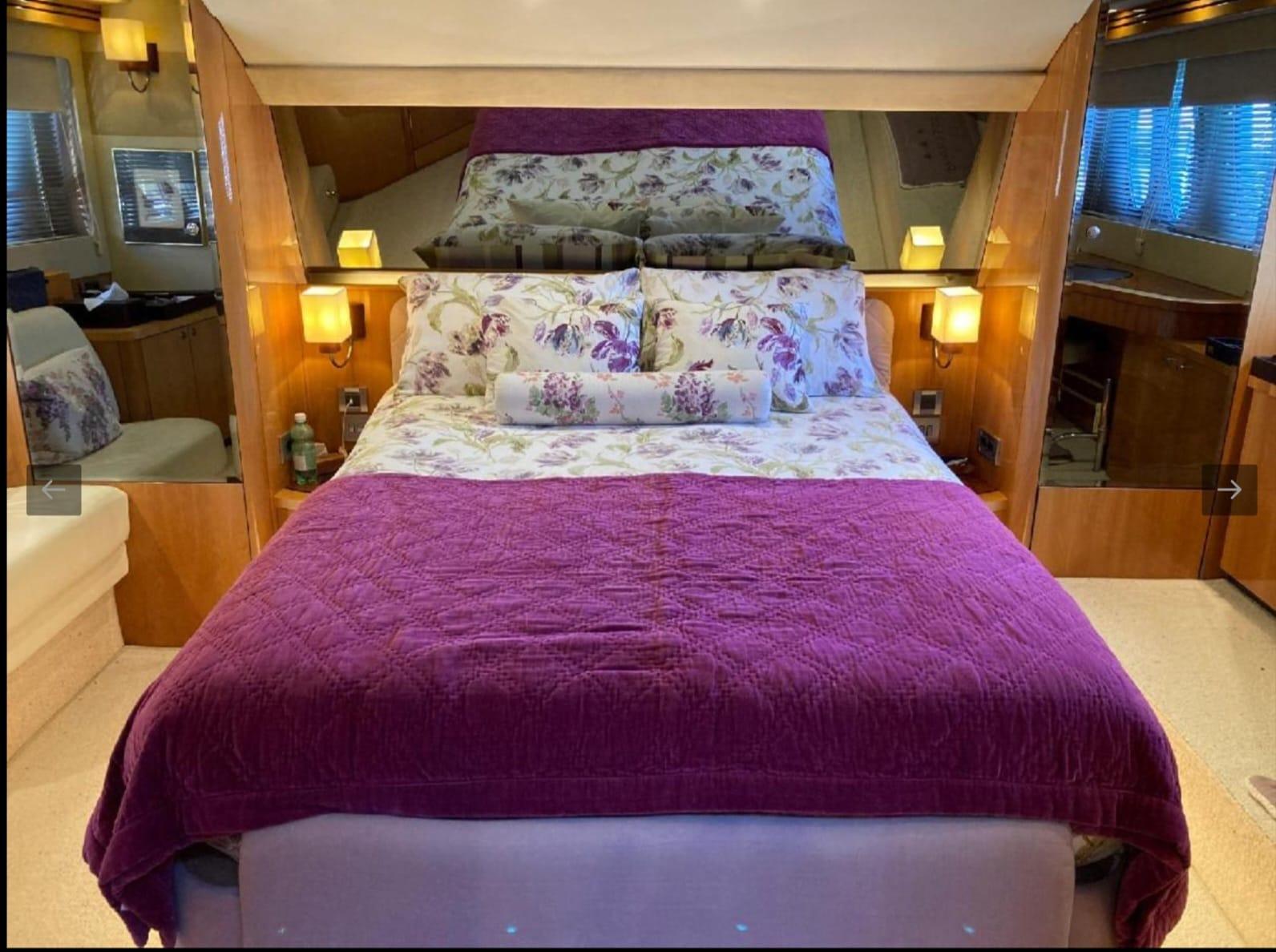 Luxurious bedroom interior of 2005 Sealine T60 yacht with floral bedding and warm lighting.