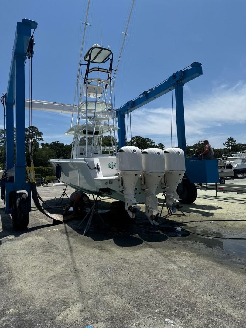 2012 Contender 39ST boat with triple outboard engines on a lift under clear sky.