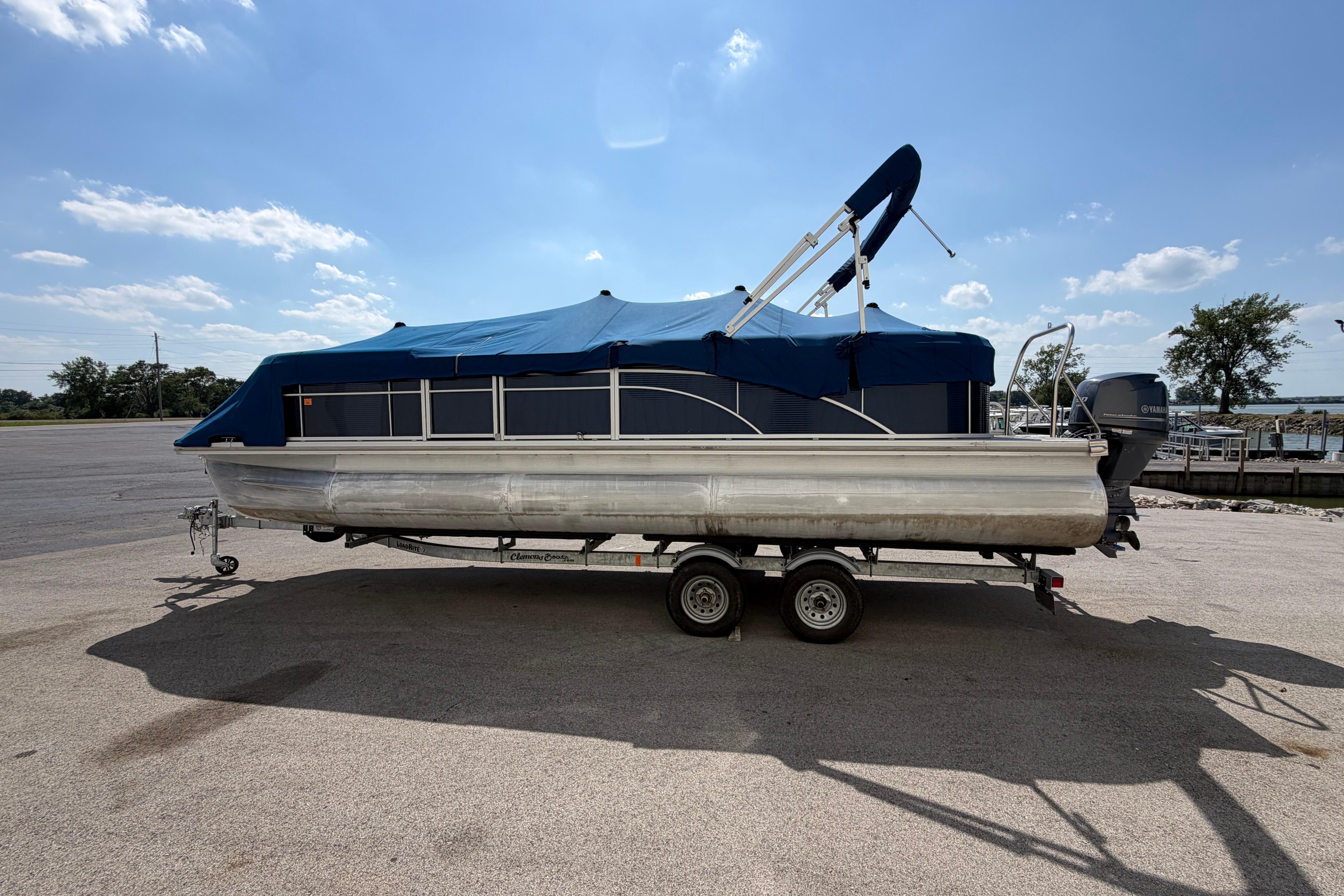2017 Bennington 25 SSXAPG pontoon boat with blue cover on trailer under clear sky.
