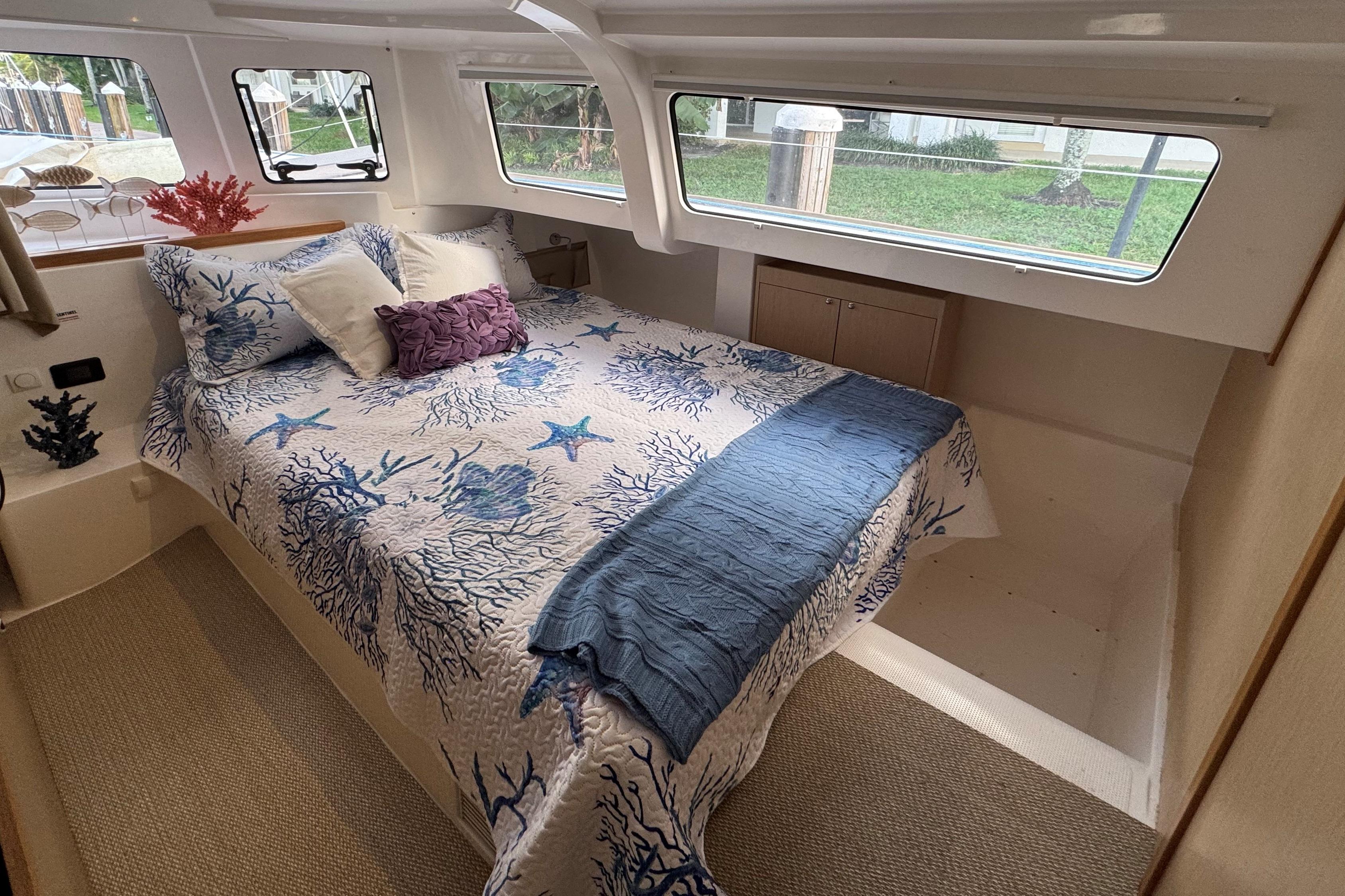 Cozy bedroom in 2023 NEEL 43 yacht with nautical-themed bedding and large windows.