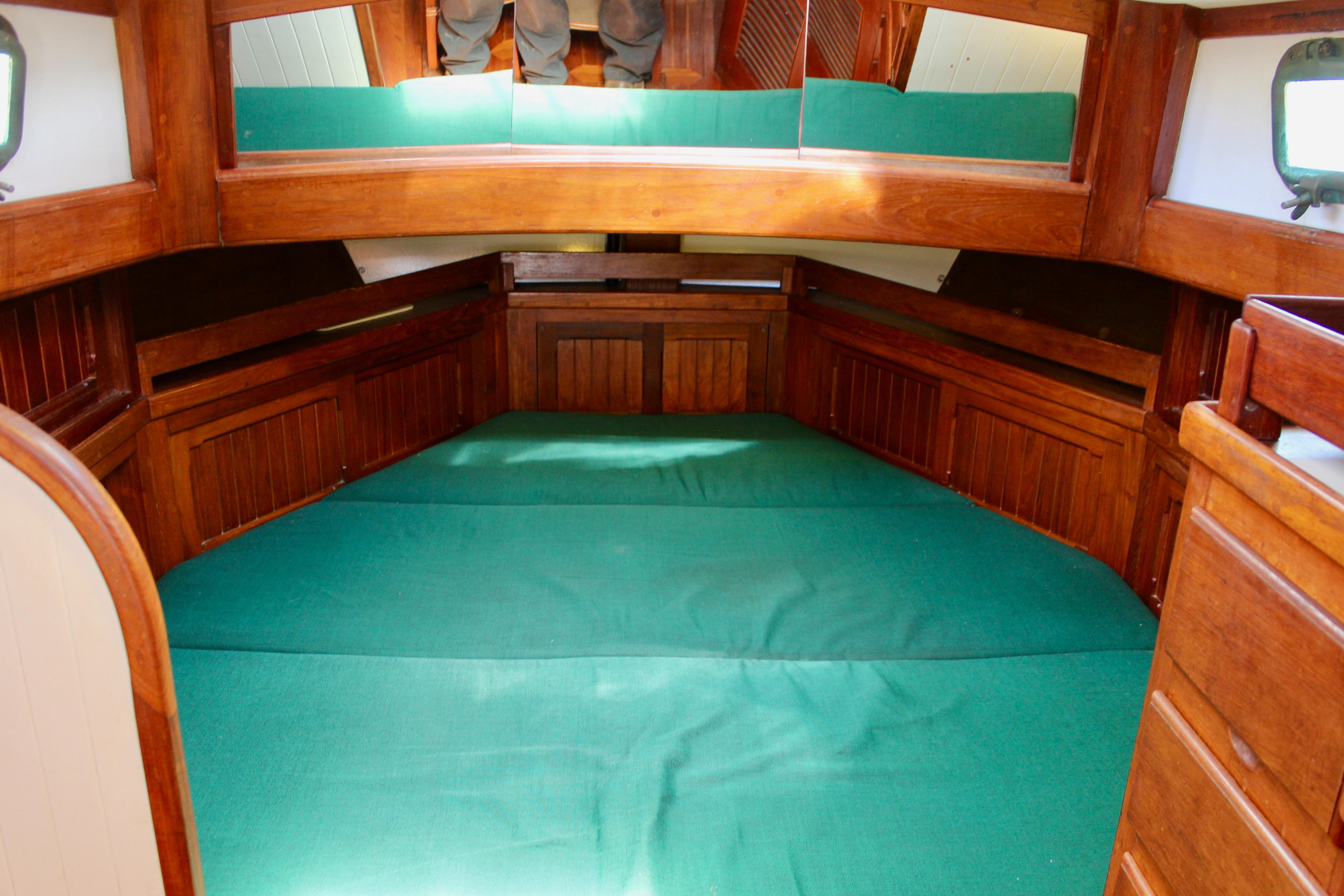 Interior cabin of 1981 Kelly Peterson 46 sailboat with green bedding and wooden finish.