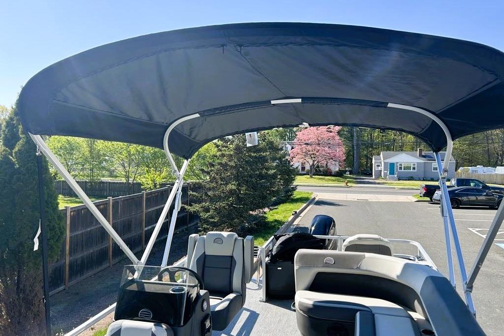 2026 Sun Tracker Bass Buggy 18 DLX pontoon boat with canopy in a residential area.