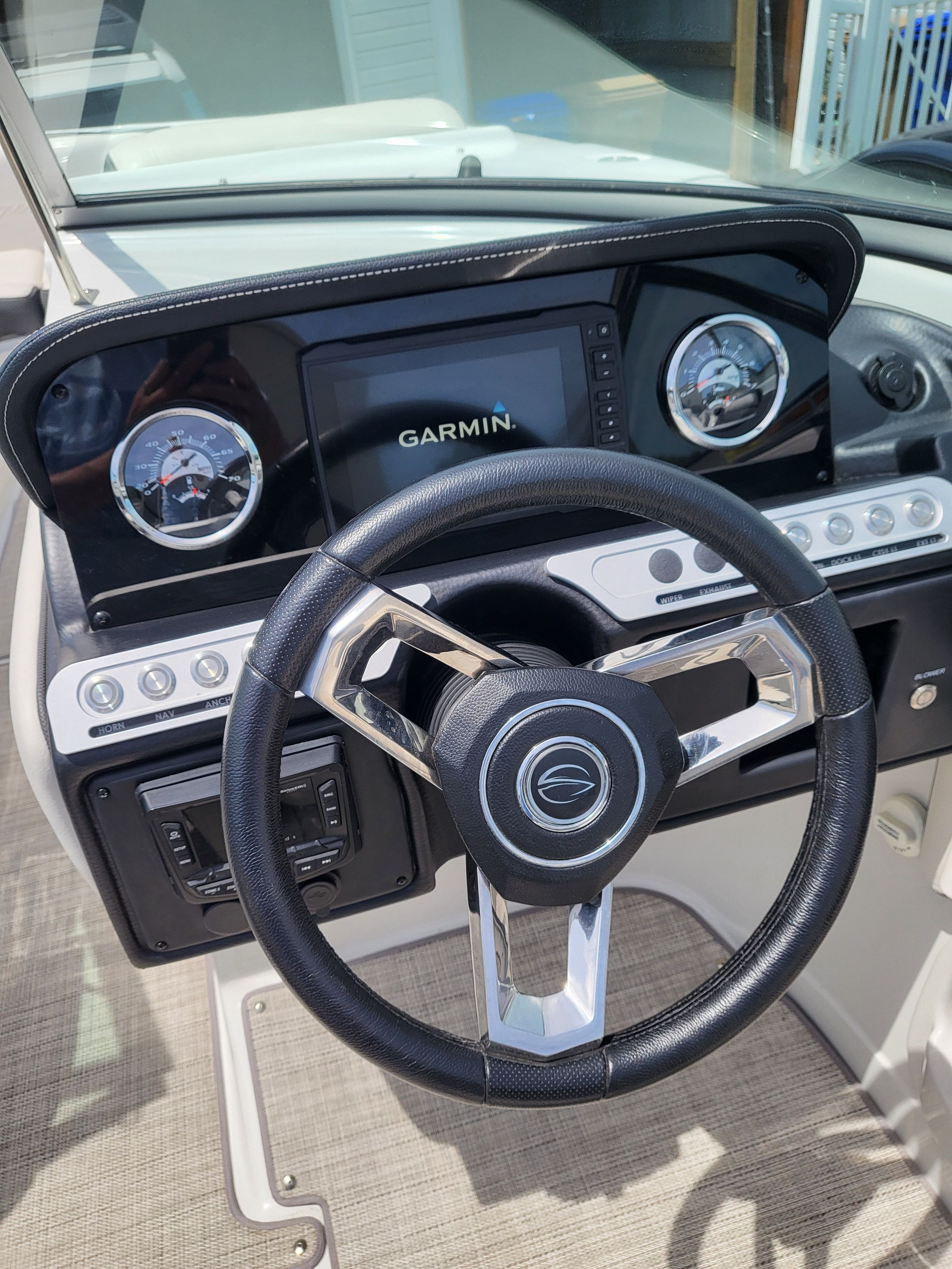 The cockpit of a Crownline 255 SS boat with a Garmin display and two round gauges.