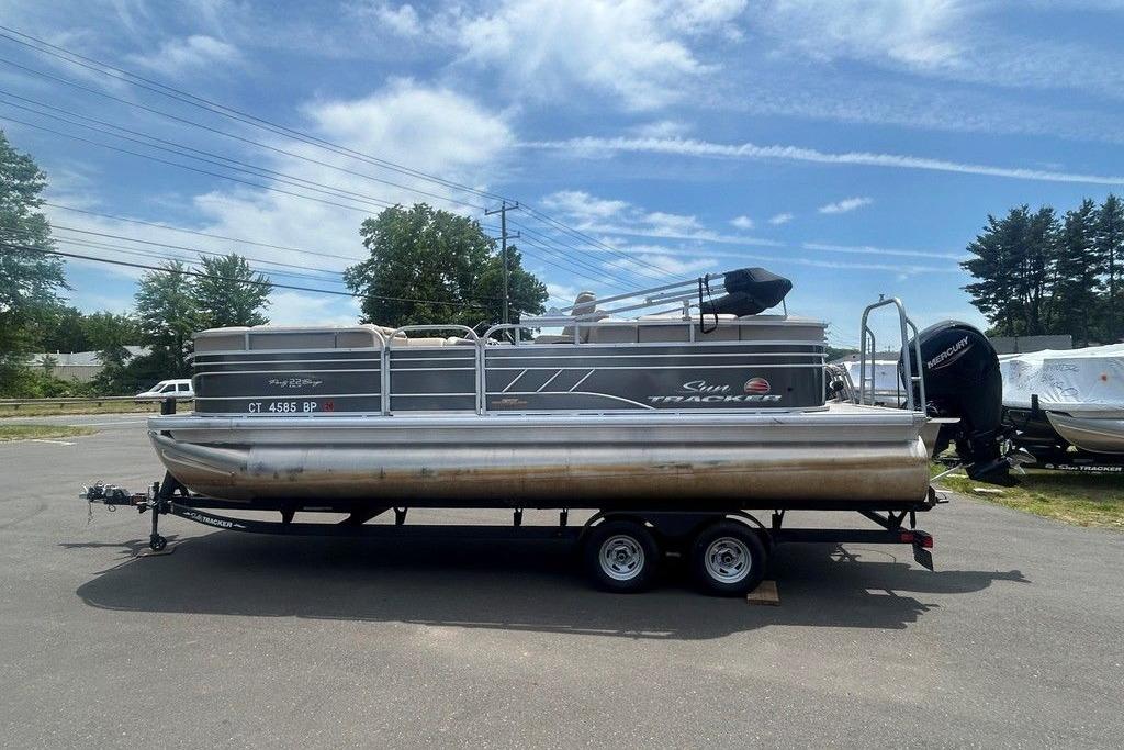 2023 Sun Tracker Party Barge 22 DLX pontoon boat on trailer, parked outdoors.