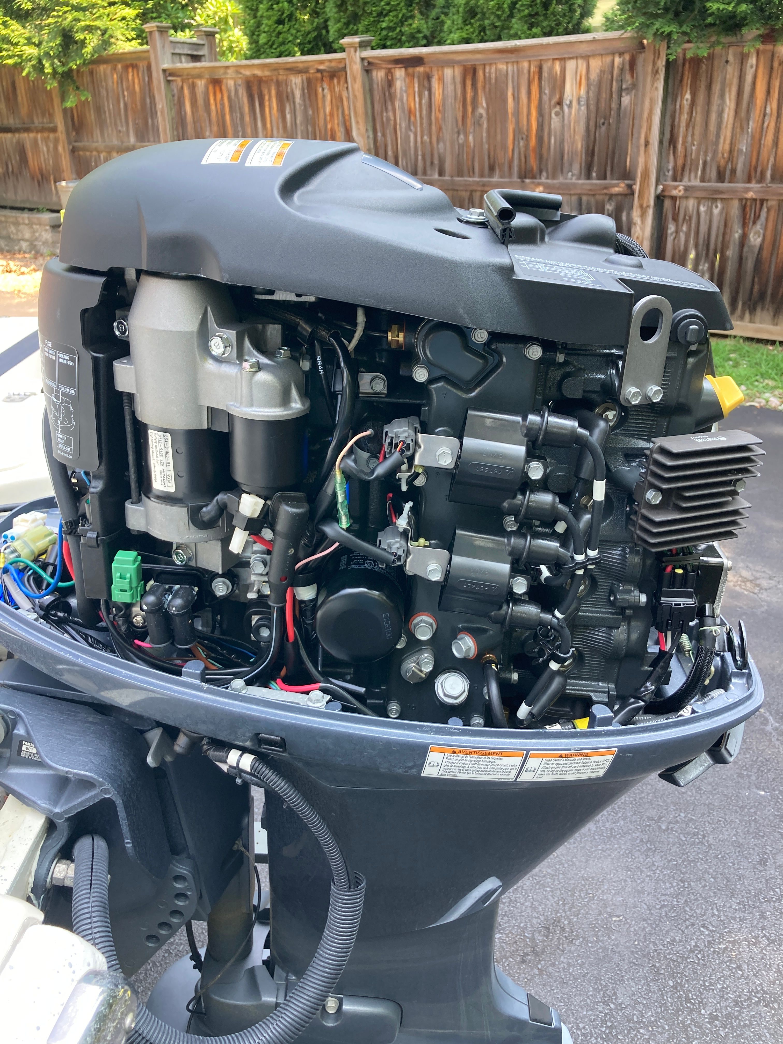 An outboard motor with visible wires and components, mounted on a boat.