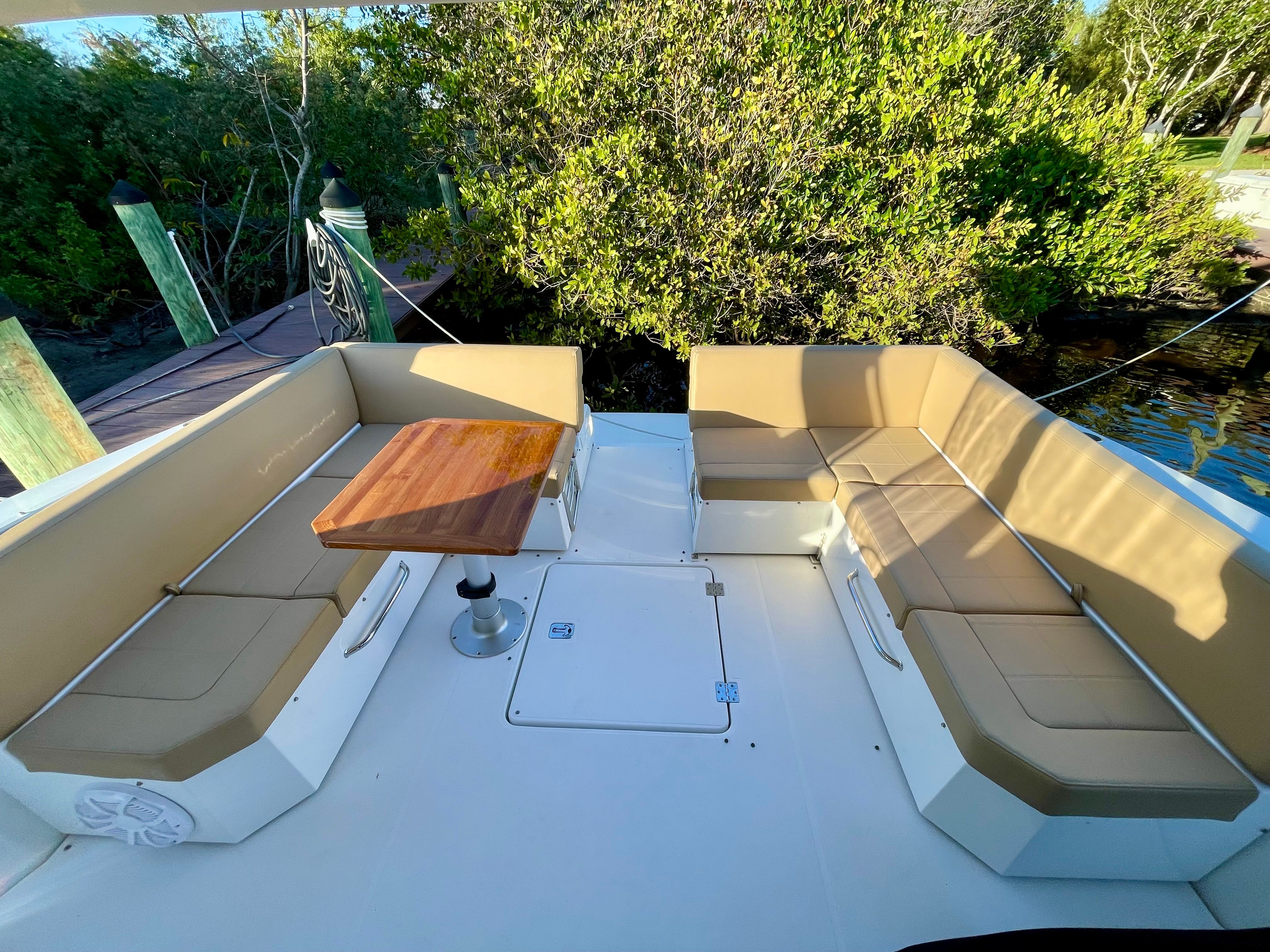 The image shows the cockpit of a 2016 Cruisers Yachts 390 Express Coupe with beige seating and a wooden table.