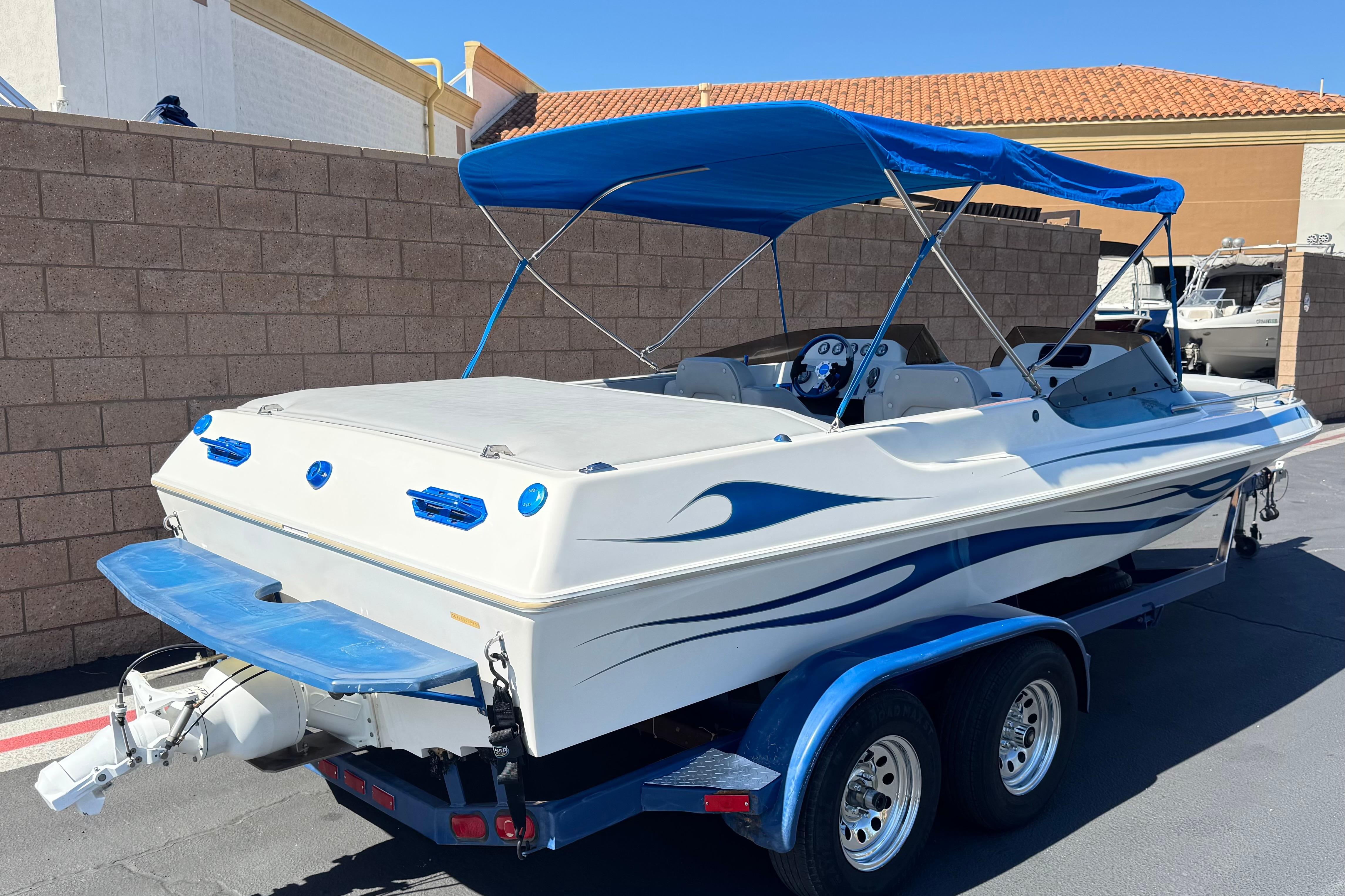 2007 Commander 2300LX boat with blue canopy on trailer, parked outdoors.