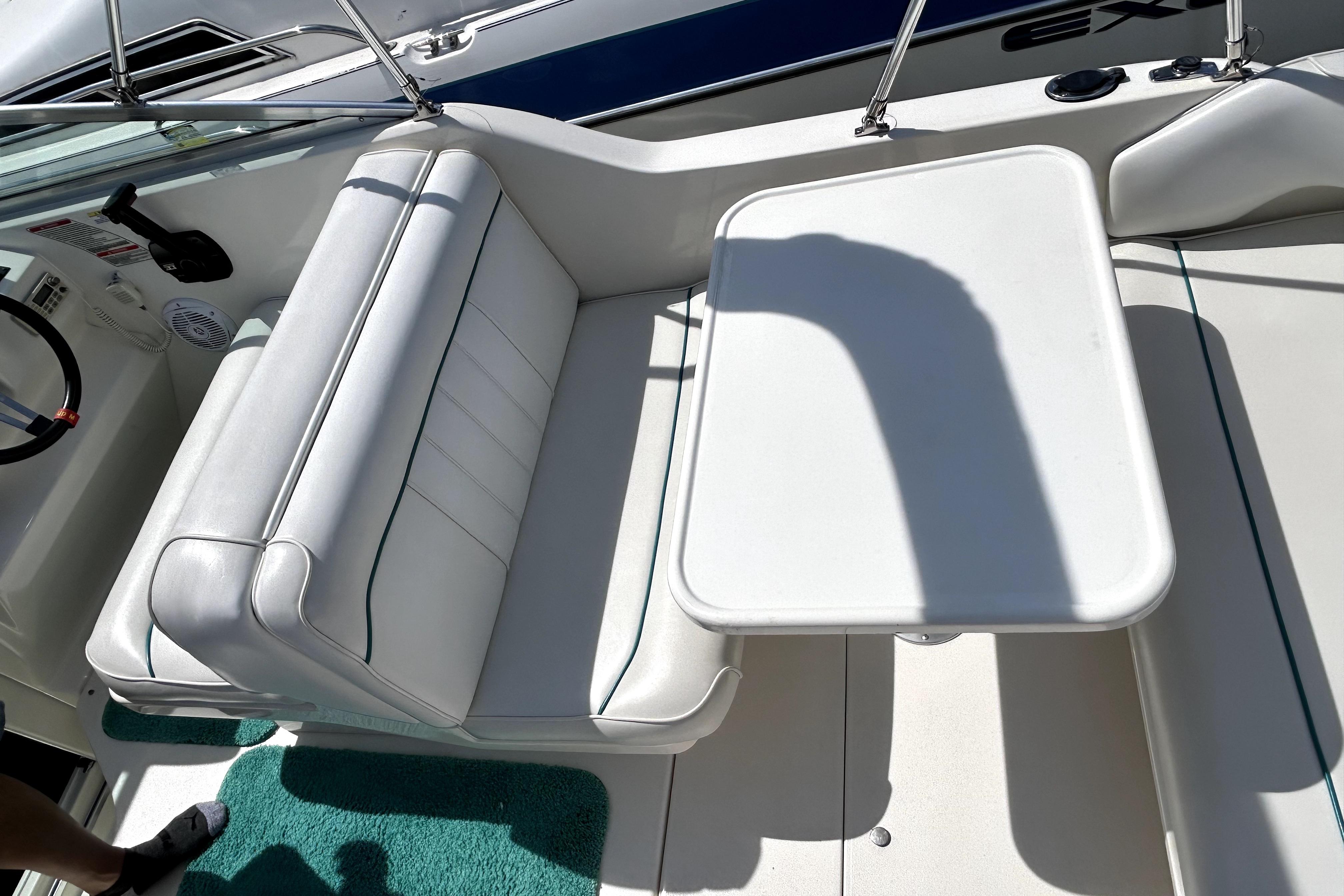 Interior seating area of a 1995 Sea Ray 250 Sundancer boat with white upholstery.