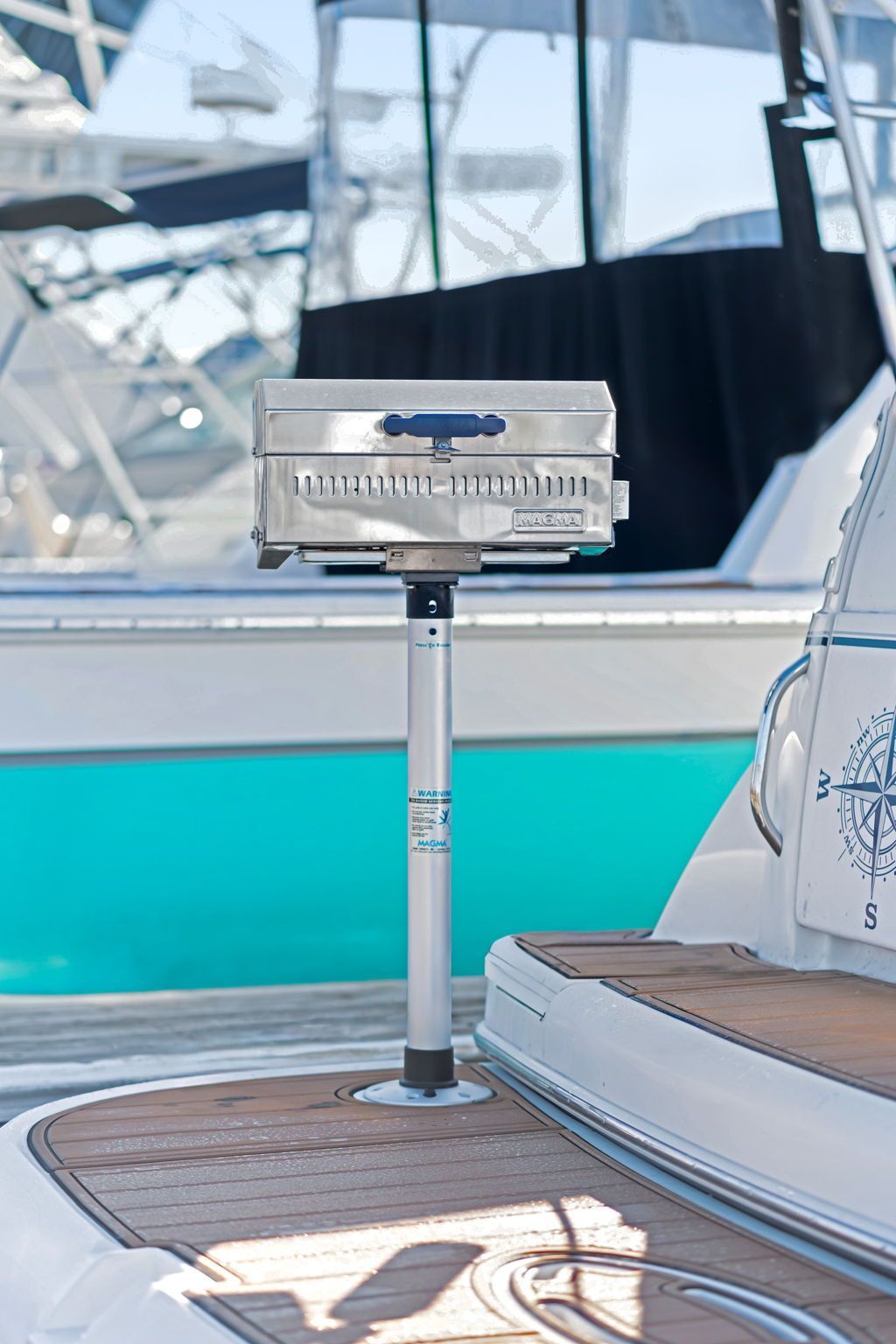A grill on a boat deck, surrounded by other boats in the marina.