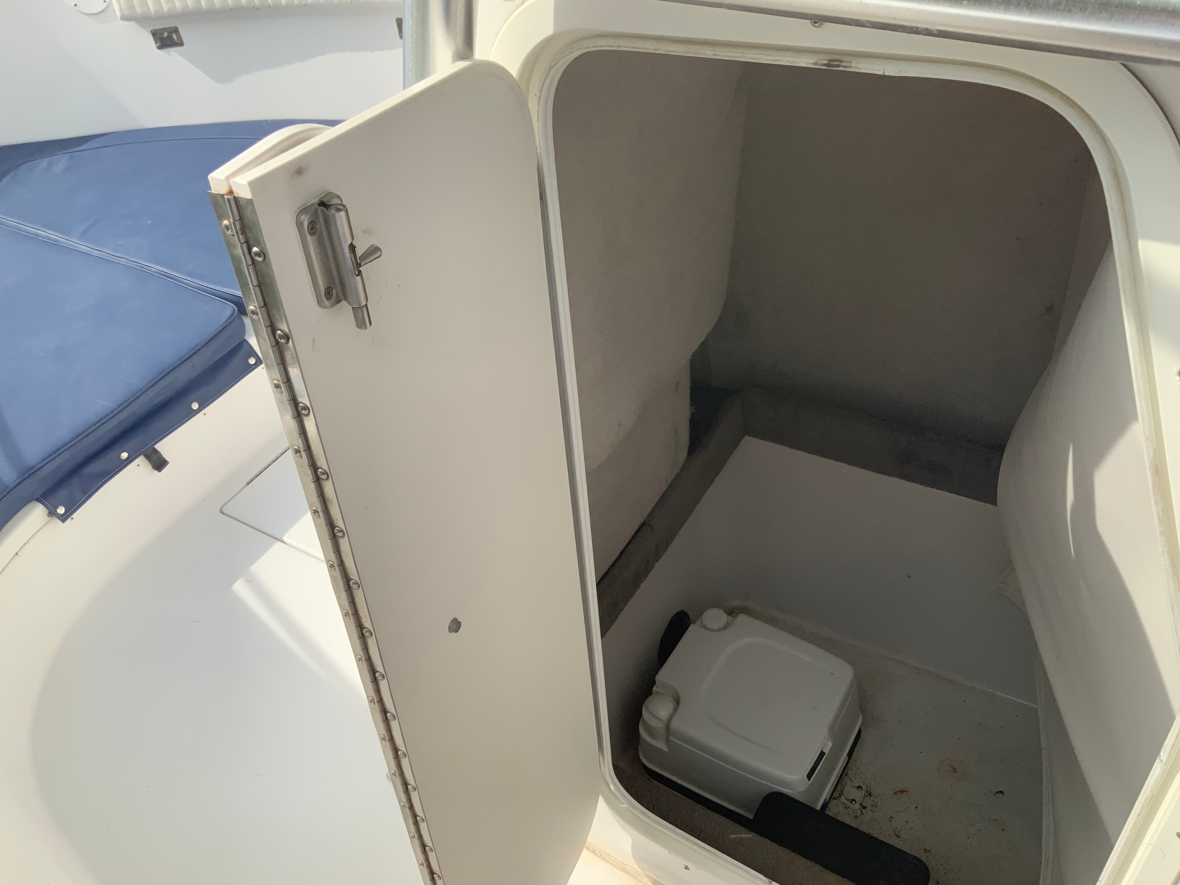 An open storage compartment on a boat with a portable toilet system.