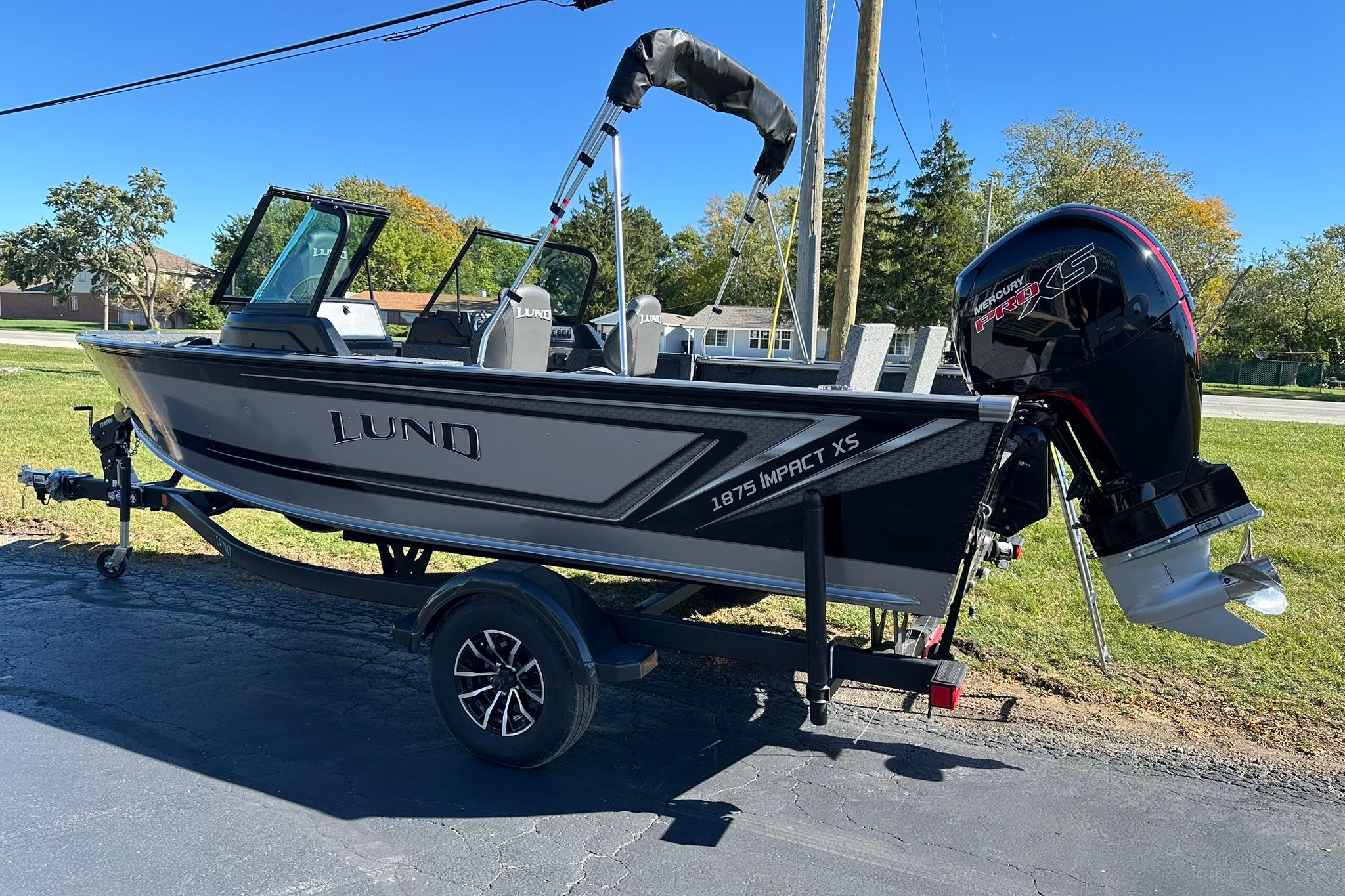 2026 Lund 1875 Impact XS Sport boat on trailer, parked outdoors on a sunny day.