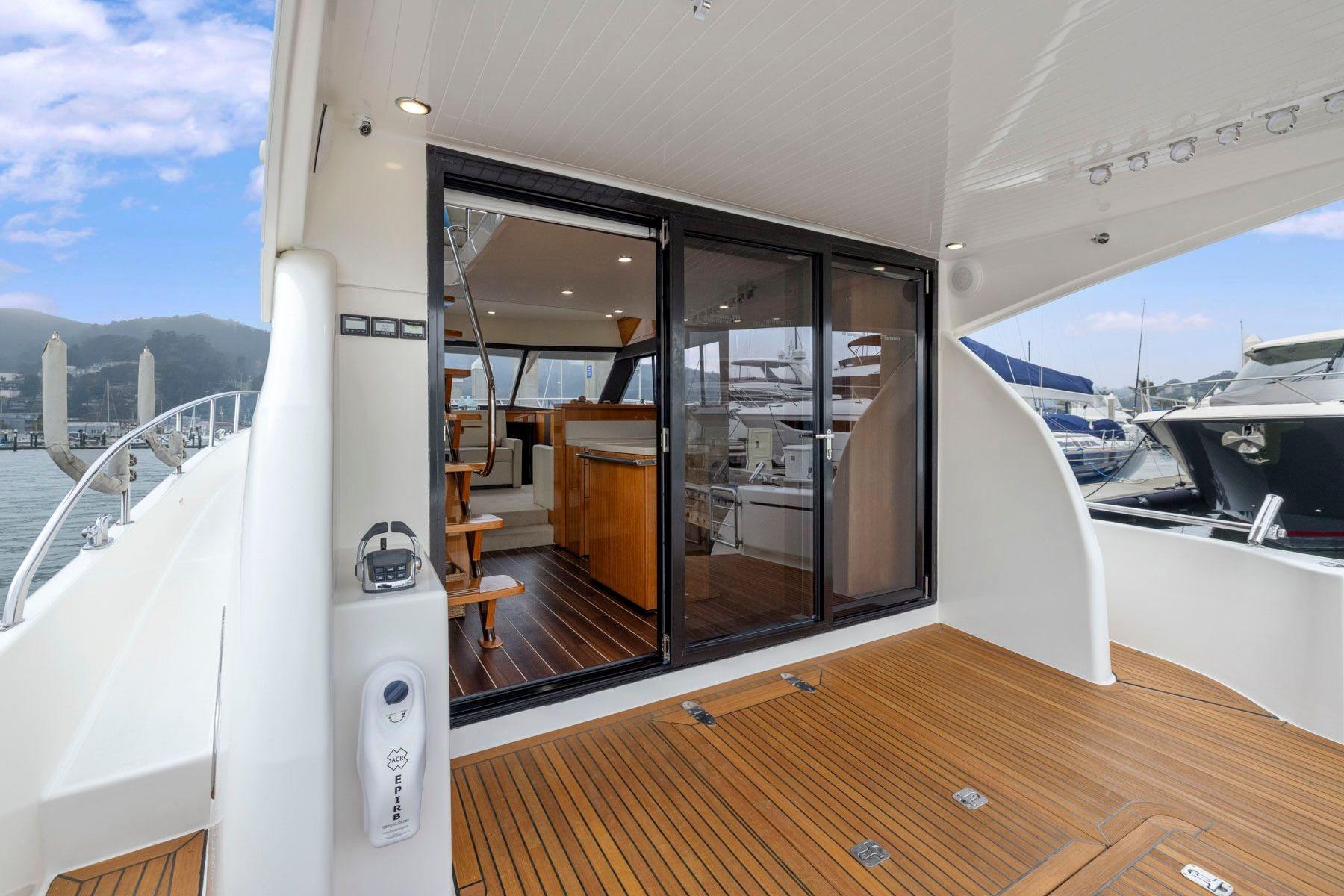 2014 Maritimo M50 yacht with open sliding doors, showcasing luxurious interior and wooden deck.