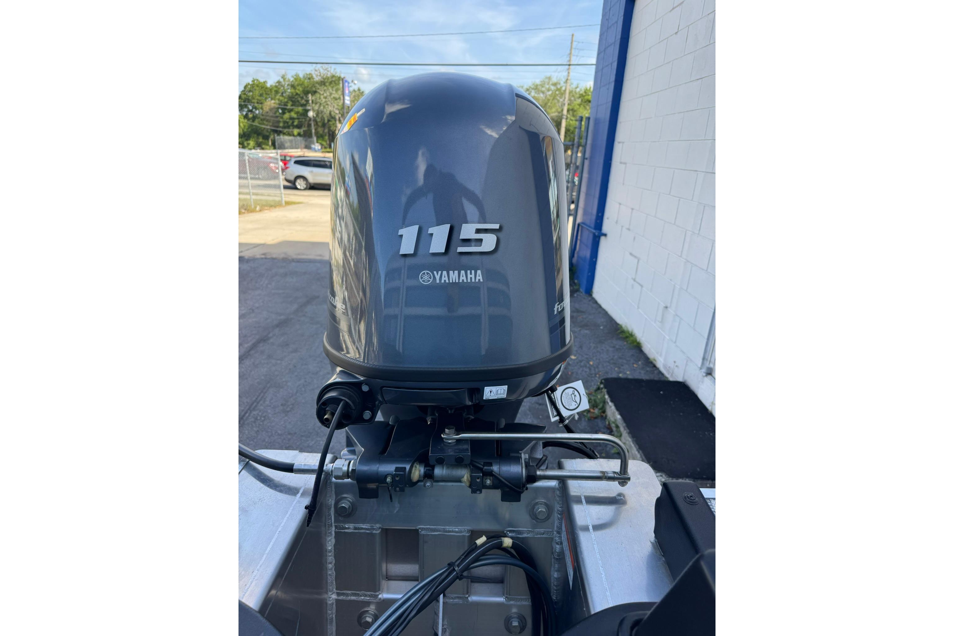 Yamaha 115 outboard motor on 2026 SunCatcher Select 22RC boat, parked outdoors.