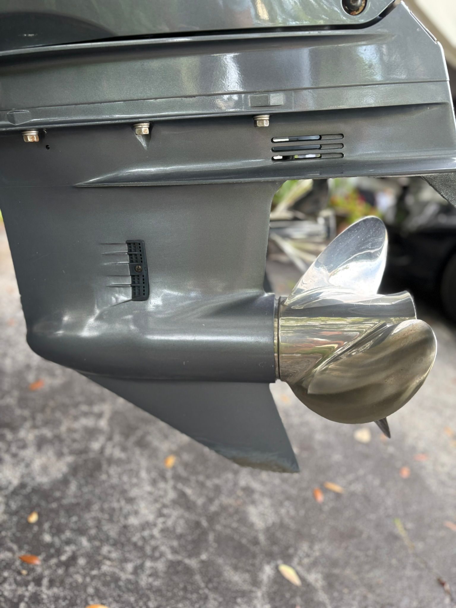 Close-up of a metal boat propeller attached to a gray outboard motor.