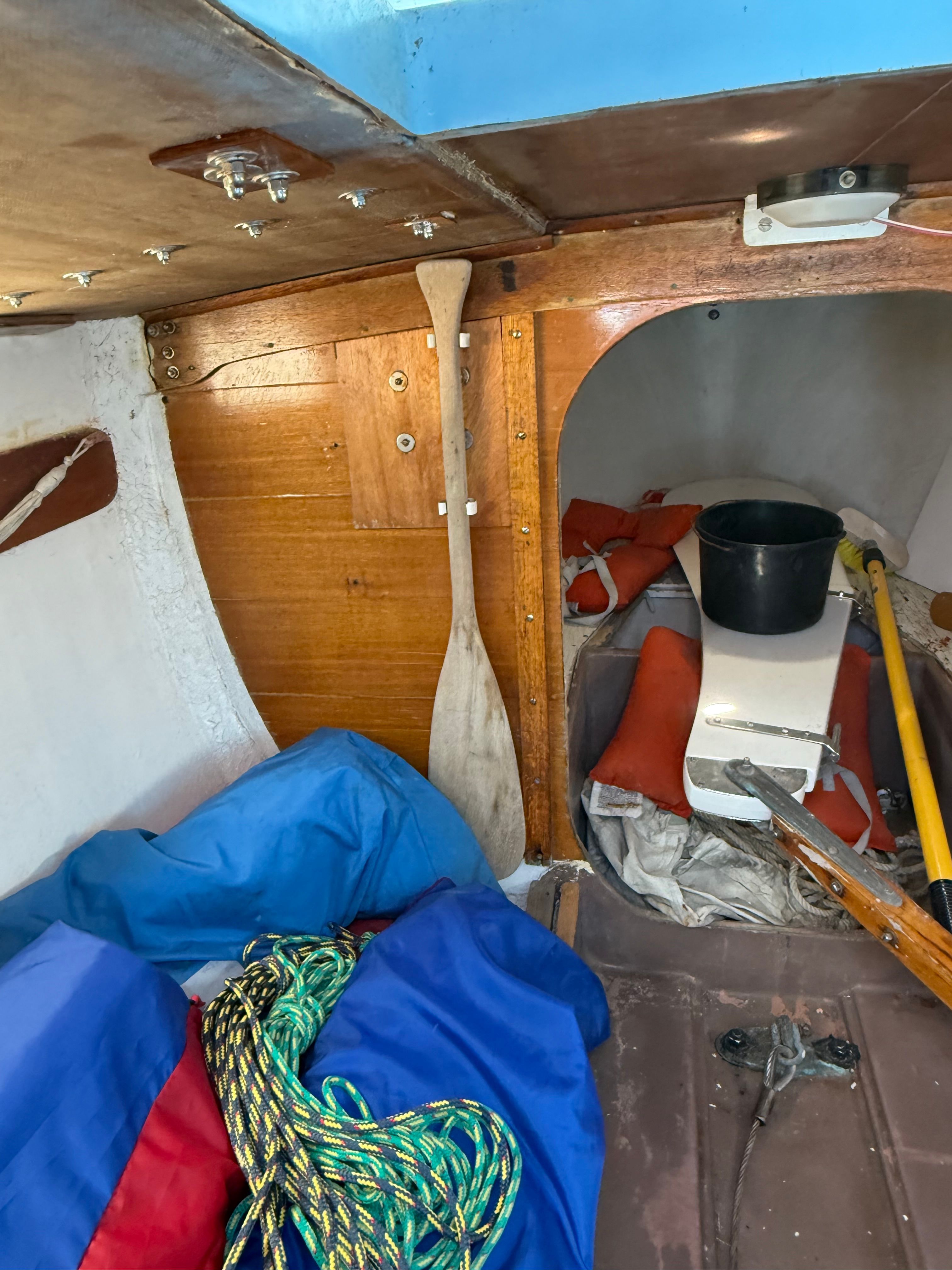 Interior of a 1965 CAL 20 sailboat with a paddle and equipment.