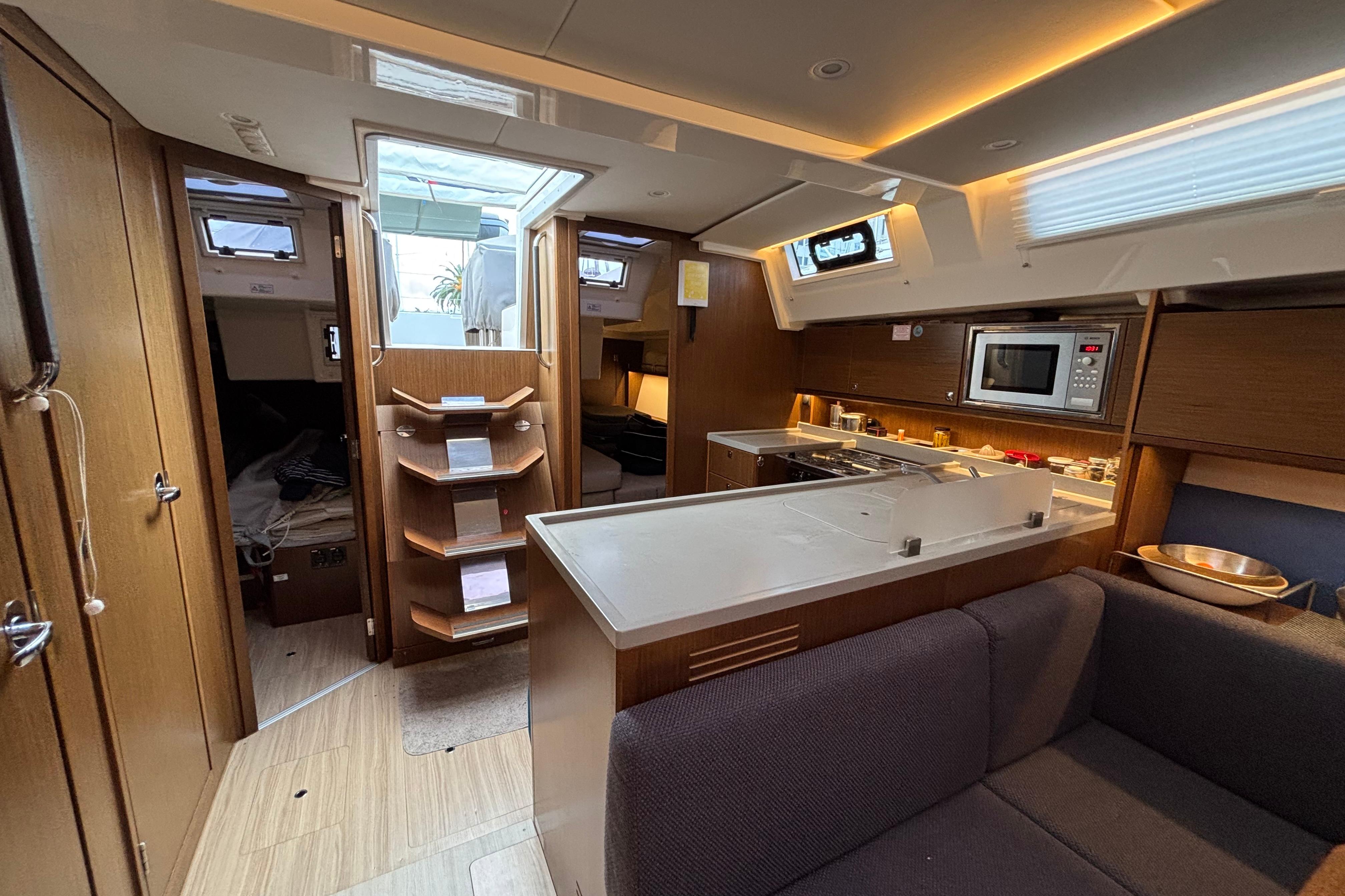 2019 Bavaria C45 yacht interior with modern kitchen, cozy seating, and wooden cabinetry.