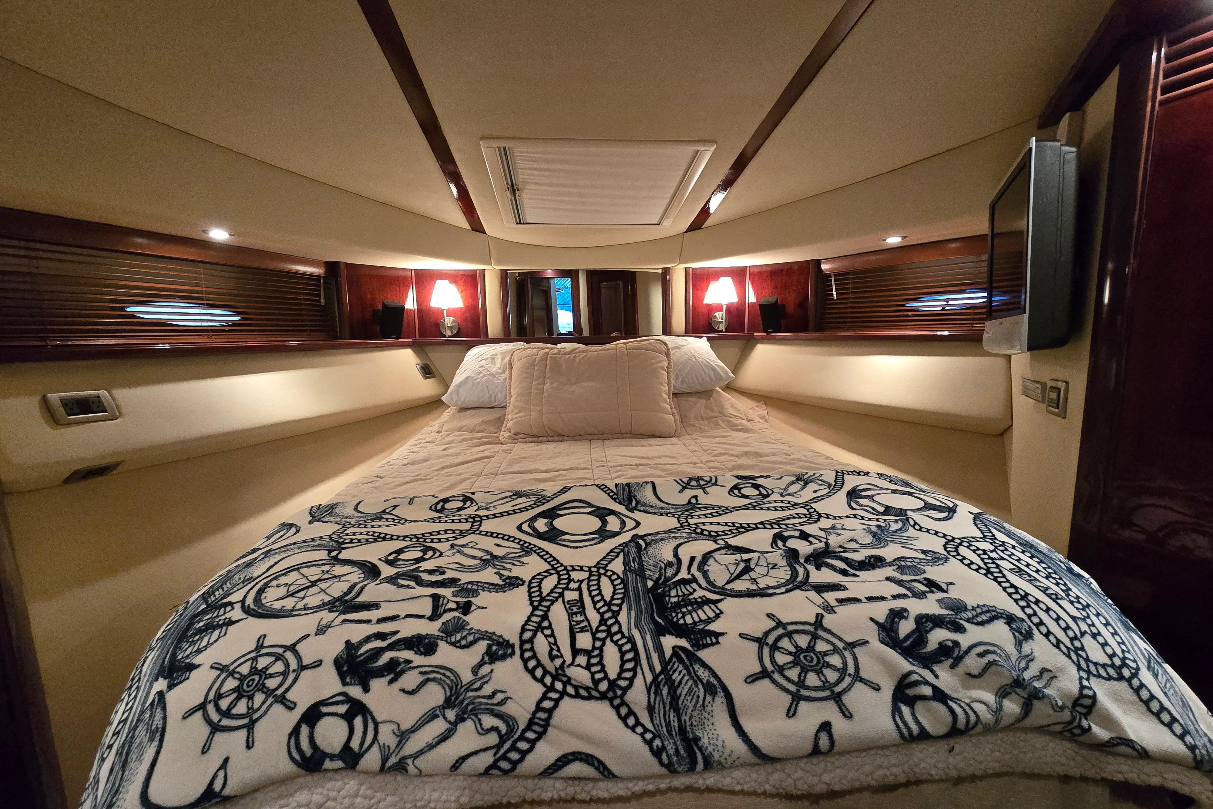 Luxurious bedroom interior of 2007 Sea Ray 52 Sedan Bridge yacht with nautical-themed bedding.