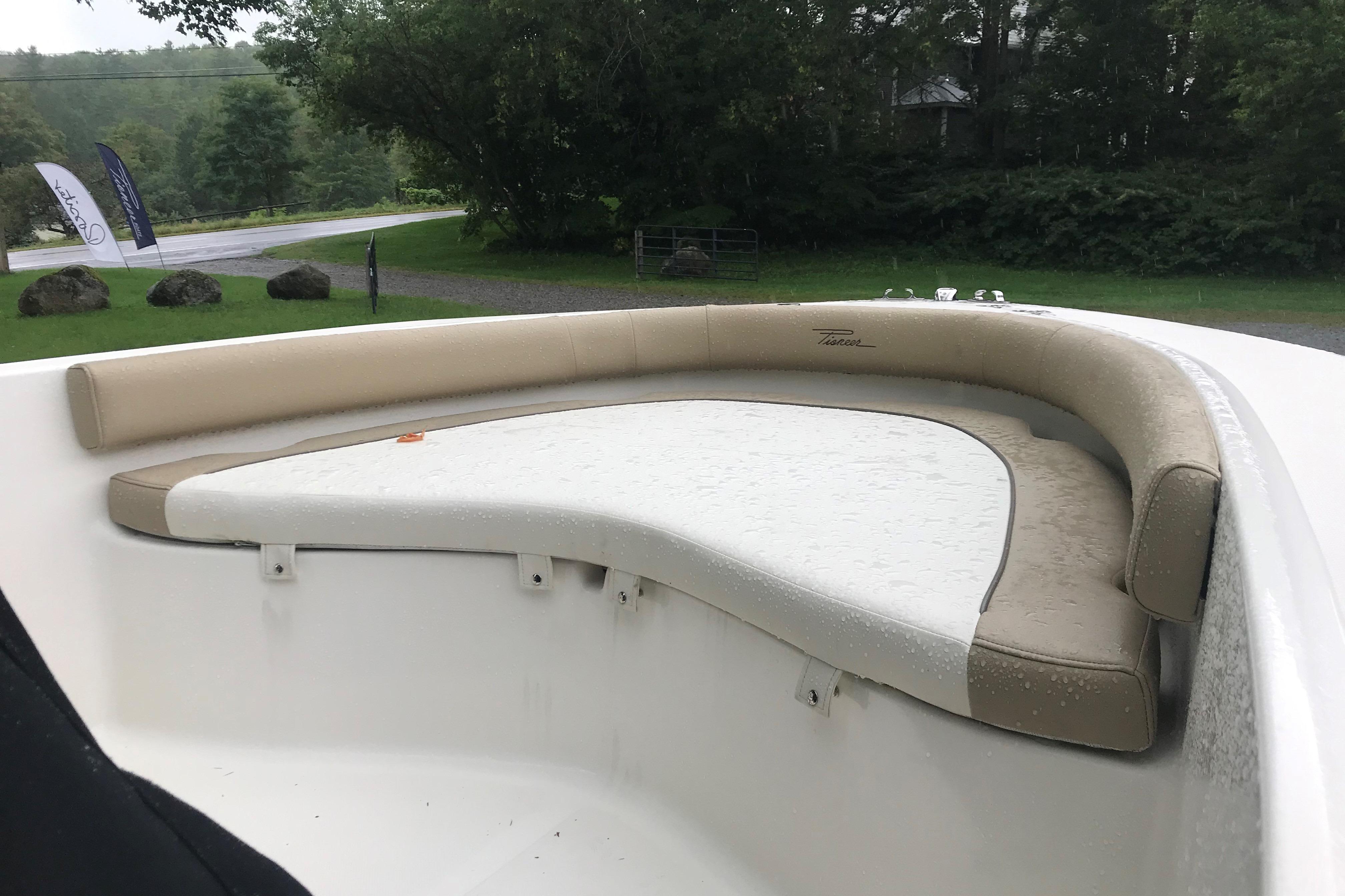 2026 Pioneer 180 Islander boat with cushioned seating, outdoors in a lush green setting.