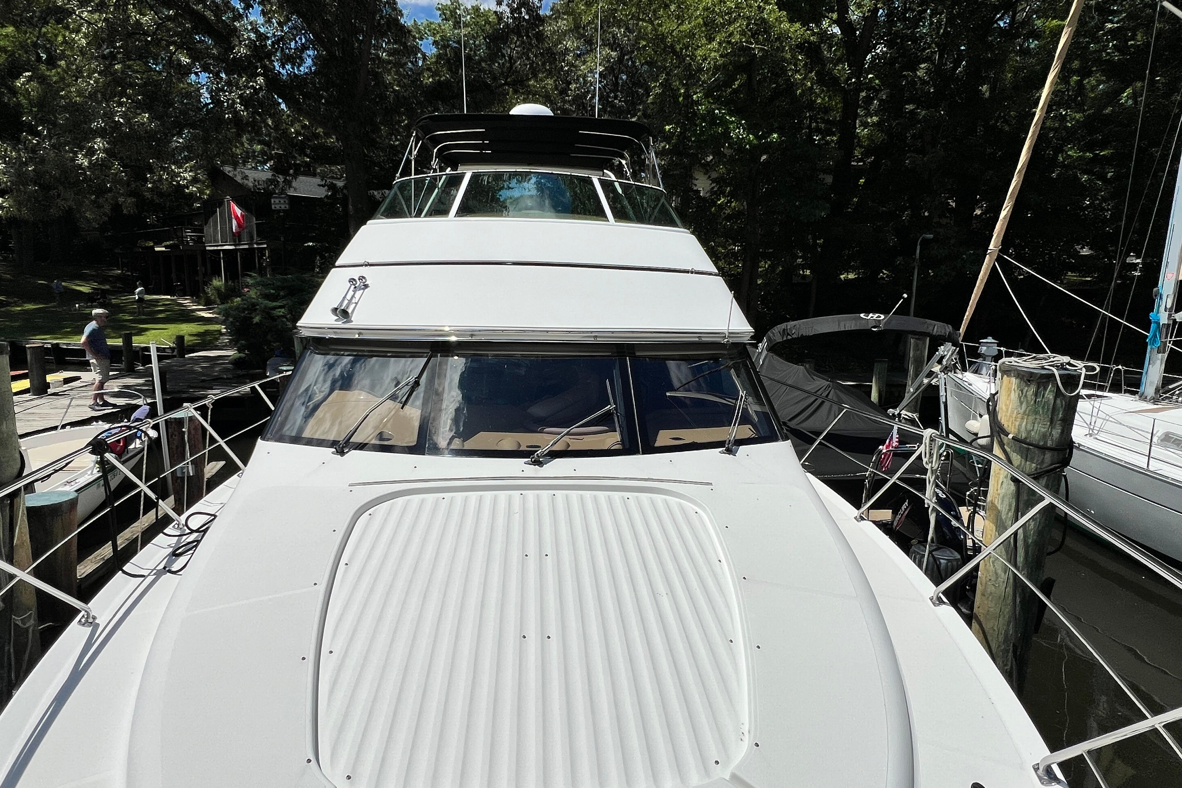 2003 Carver 450 Voyager Pilothouse yacht docked in a marina surrounded by trees.
