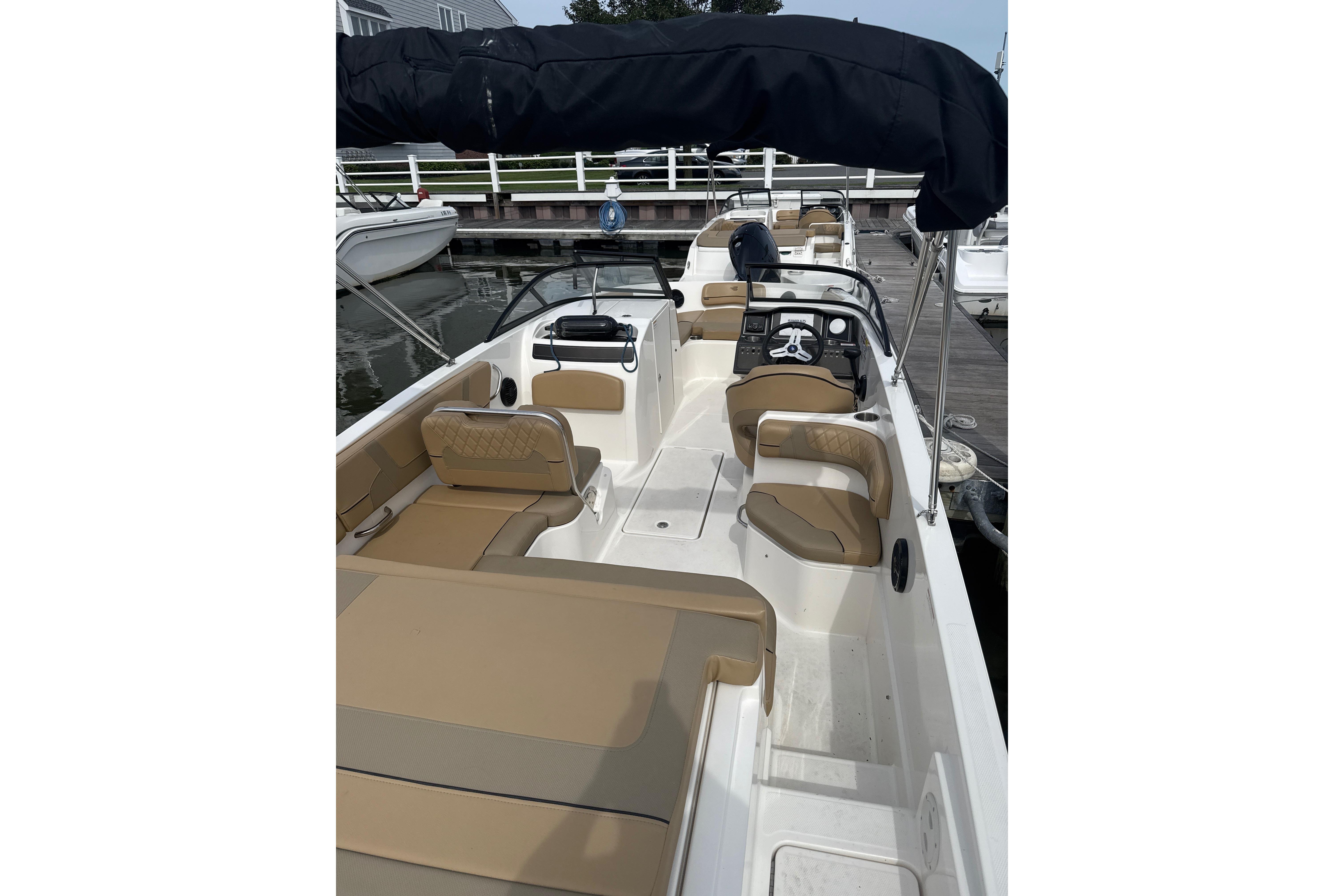 2025 Bayliner VR6 Bowrider OB with tan seating and black canopy at dock.