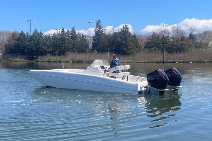 2025 Hustler 25 C3 Speedfish boat on calm water with dual outboard engines.
