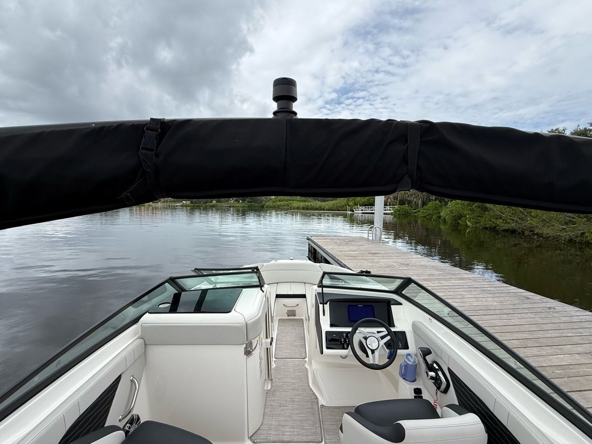 The image shows the cockpit of a 2024 Sea Ray SPX 230 Outboard. It is docked at a calm pier.