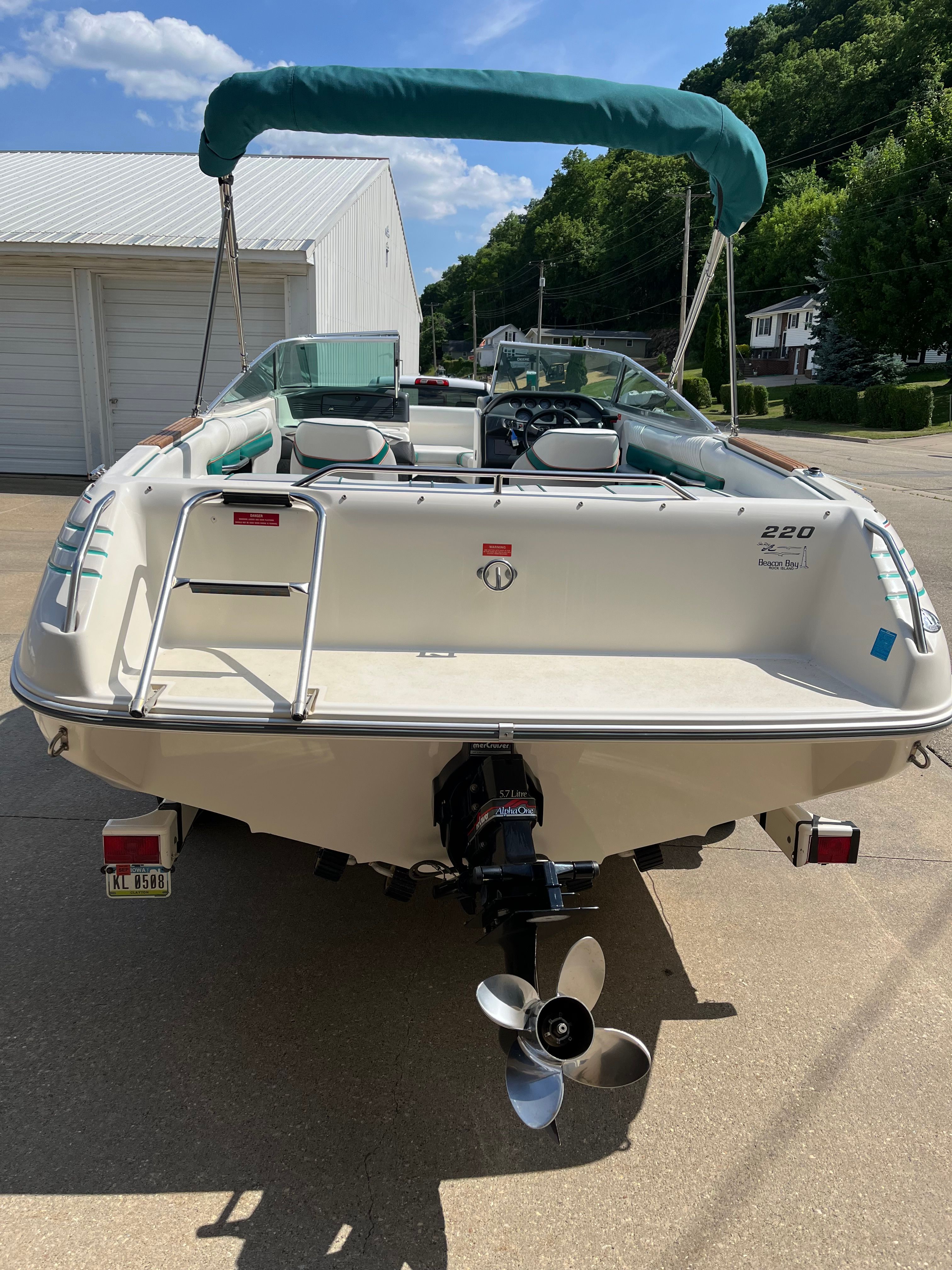 A Sea Ray 220 Bow Rider boat is parked on a driveway.