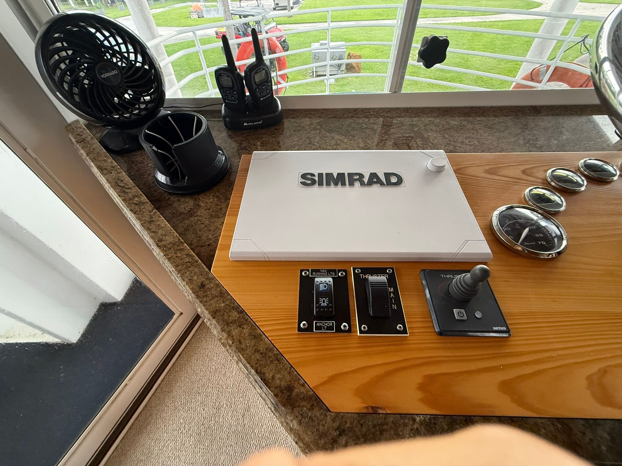 The image shows a boat helm with Simrad navigation system, joystick, and radios.