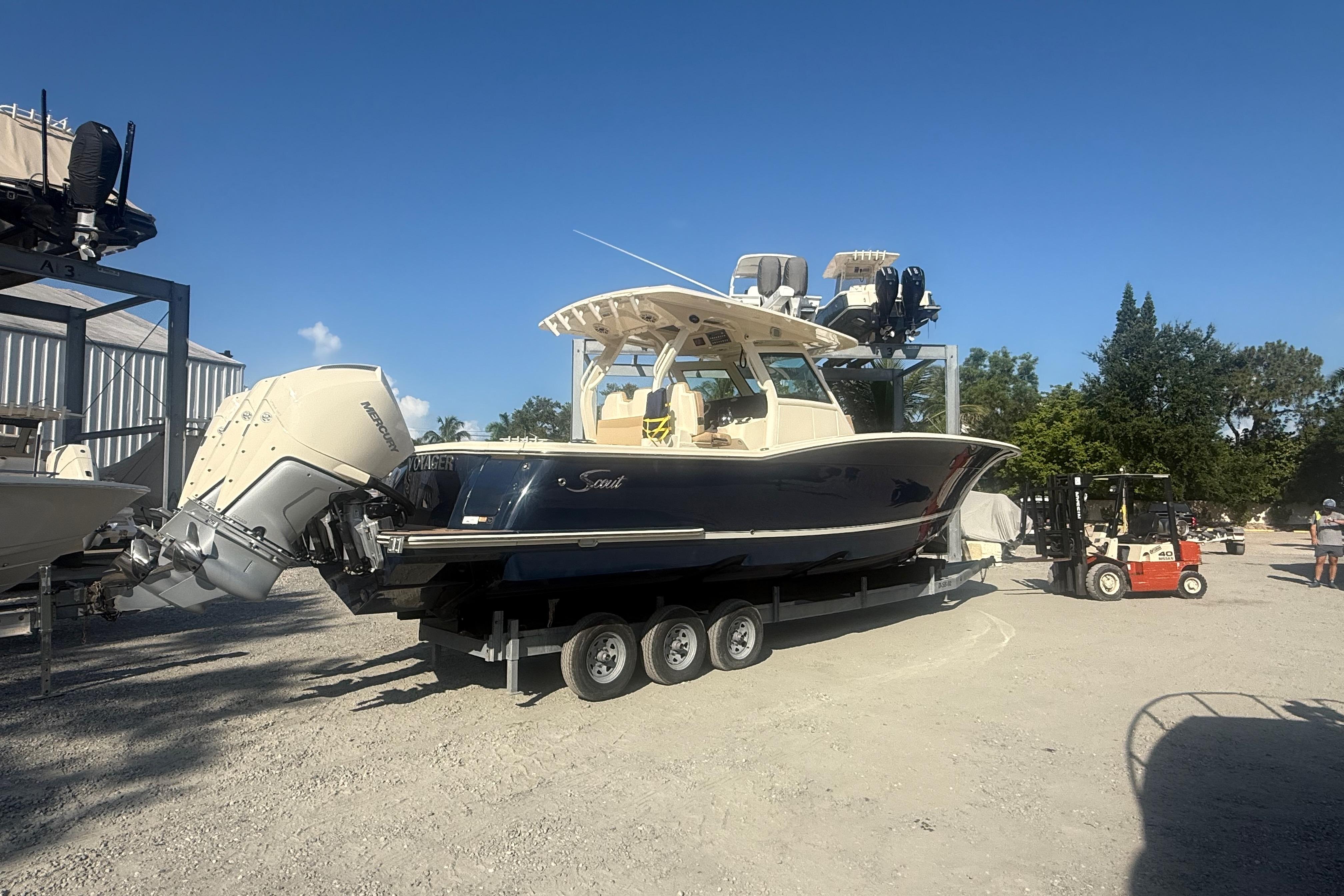 2022 Scout 355 LXF boat on trailer with triple outboard engines in a sunny marina.