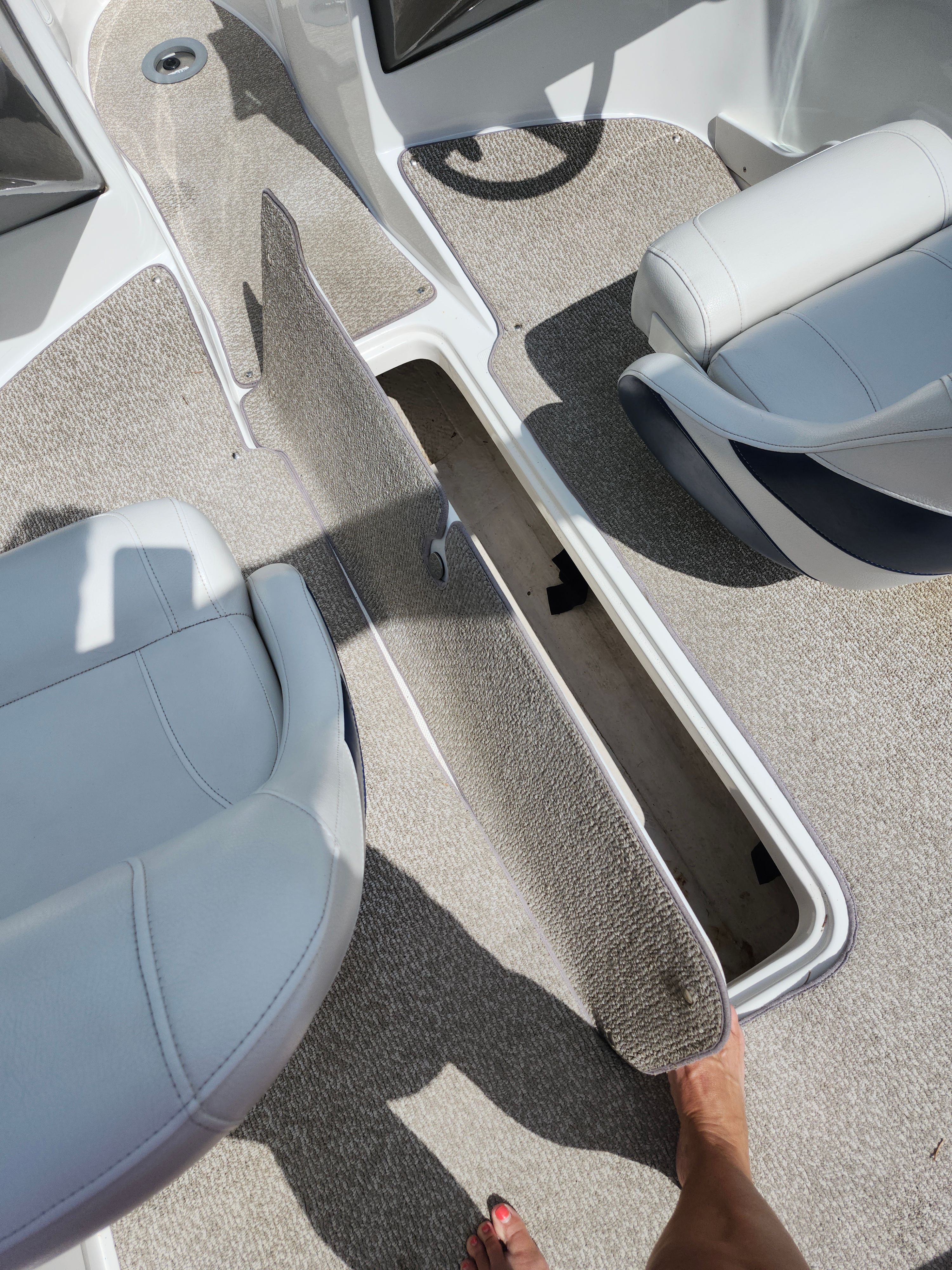 Interior view of a boat with gray carpet flooring and white seats.