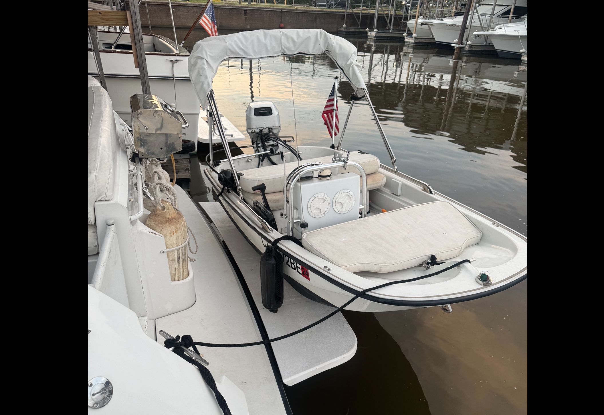 A small boat with a sunshade is docked. It features white upholstery and a US flag.