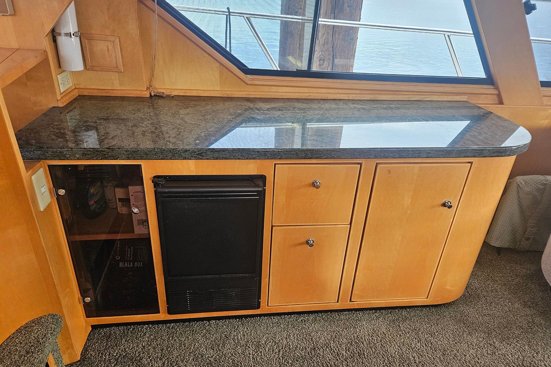 Wooden cabinet with granite countertop and mini fridge on a 1995 Symbol 55 boat.