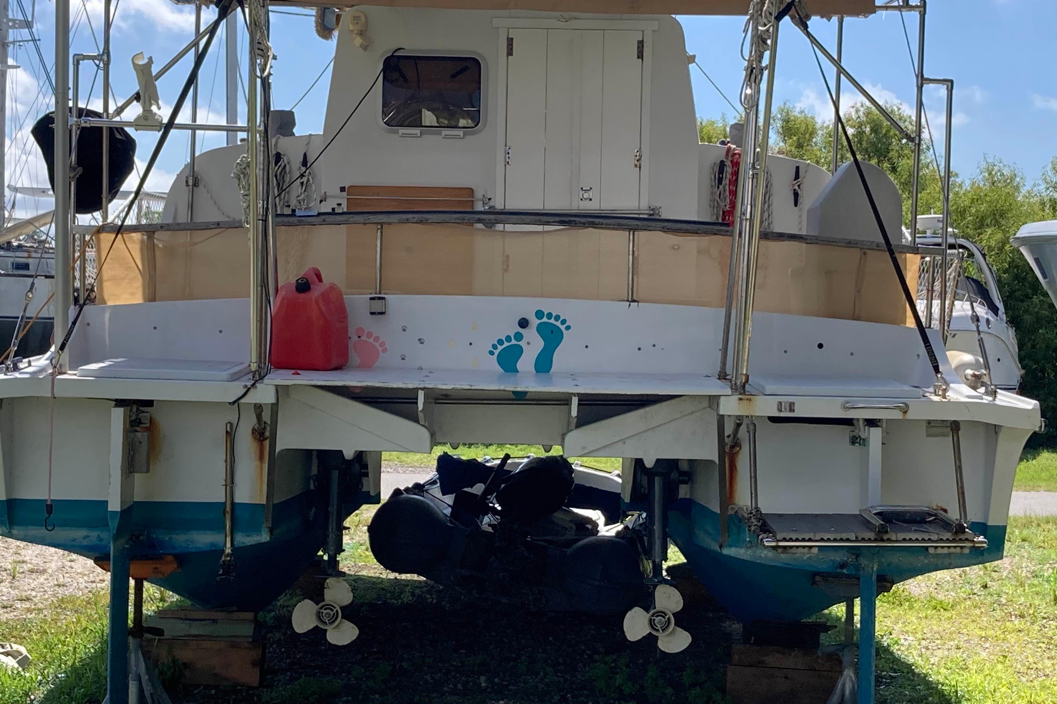 1976 Catalac 9 Meter catamaran on land, featuring dual propellers and colorful footprints.