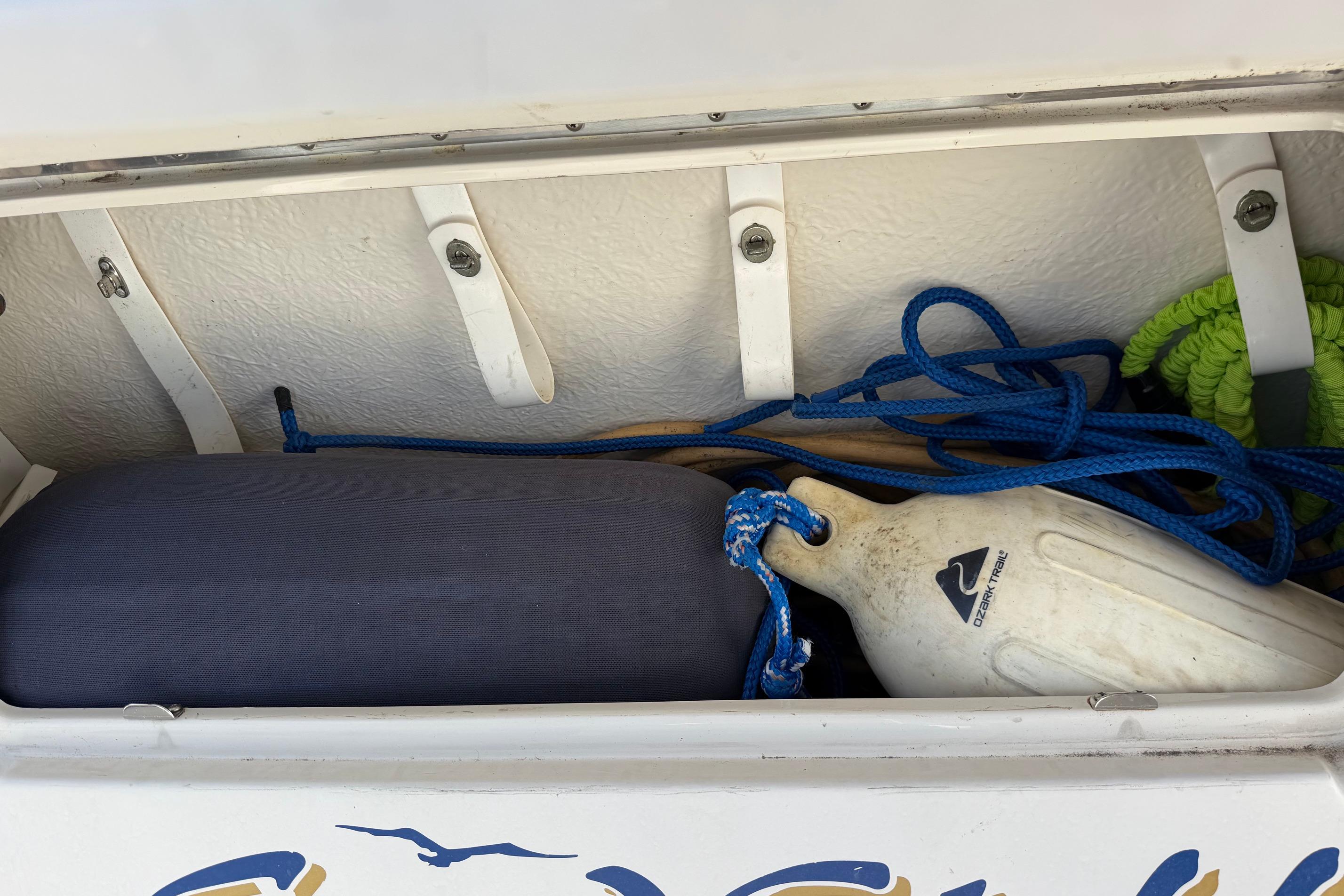 Storage compartment on a 2000 Sea Ray 240 Sundancer with ropes and a fender.