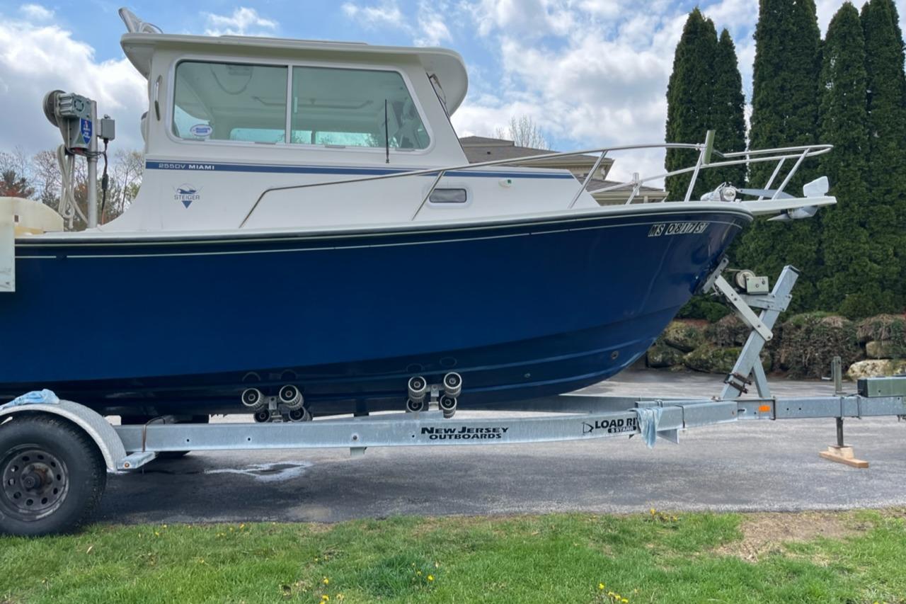 2012 Steiger Craft Miami boat on trailer, blue hull, parked outdoors.