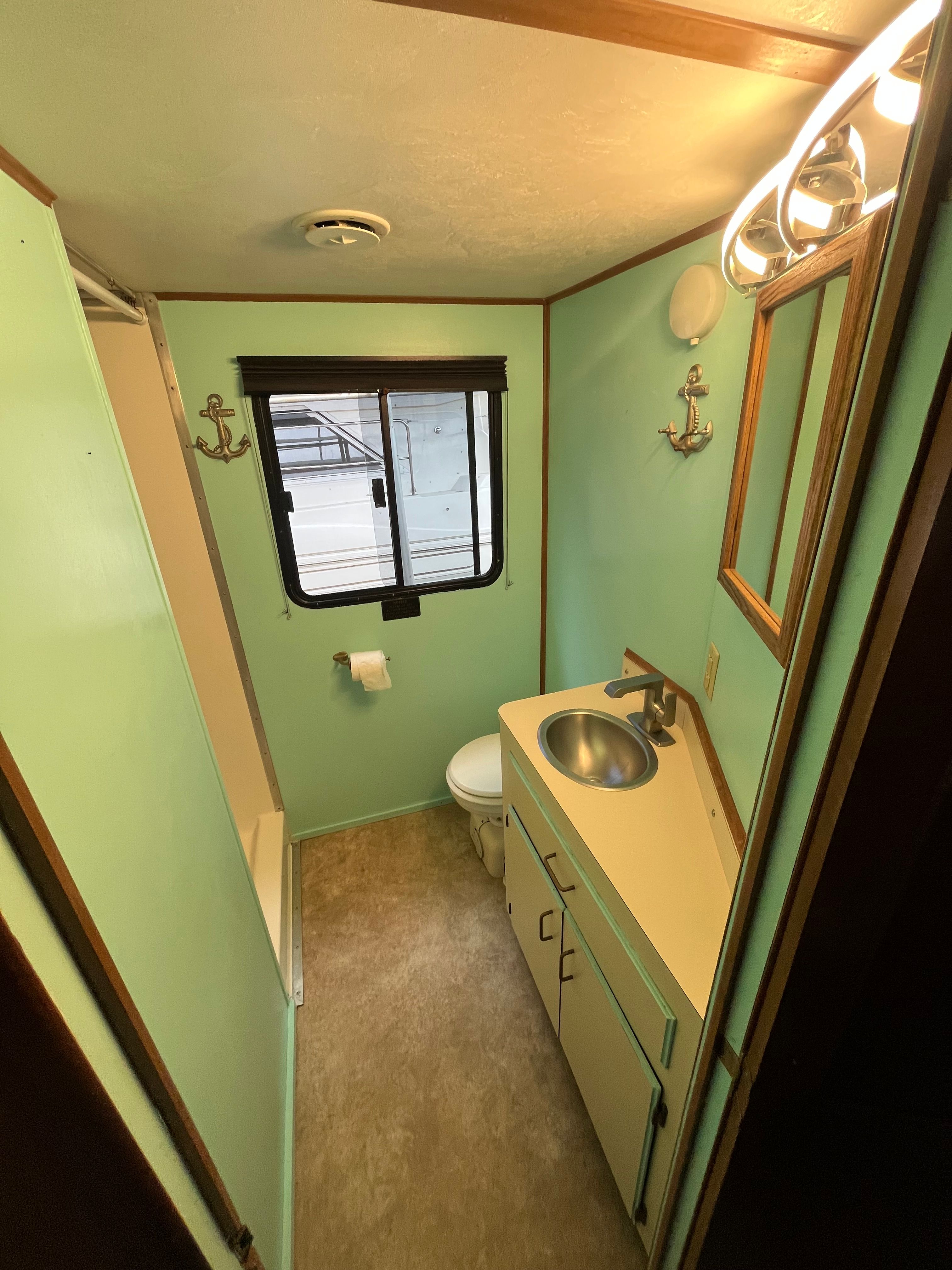 The image shows a boat bathroom with green walls, a sink, and a toilet.