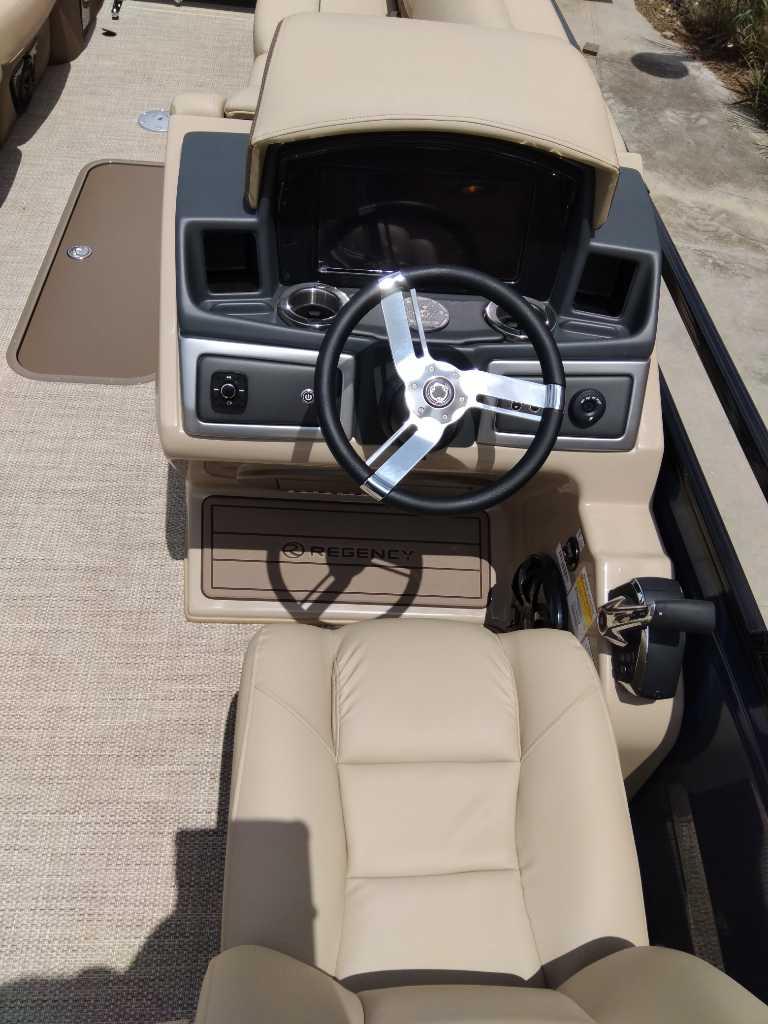 2025 Regency 250 LE3 boat cockpit with beige seating and modern steering wheel.