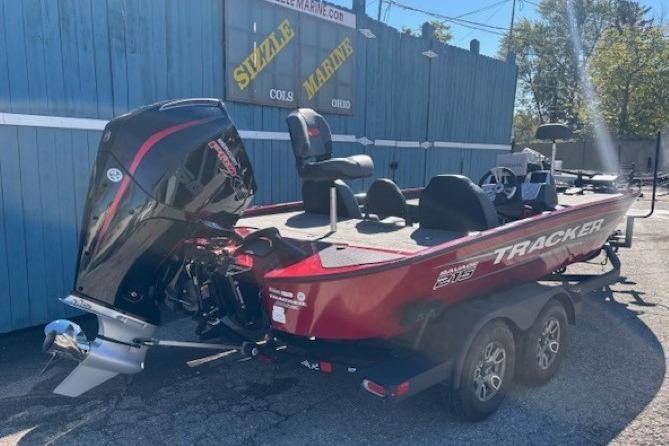 2025 Tracker Savage 215 boat in red, parked on a trailer near a blue building.