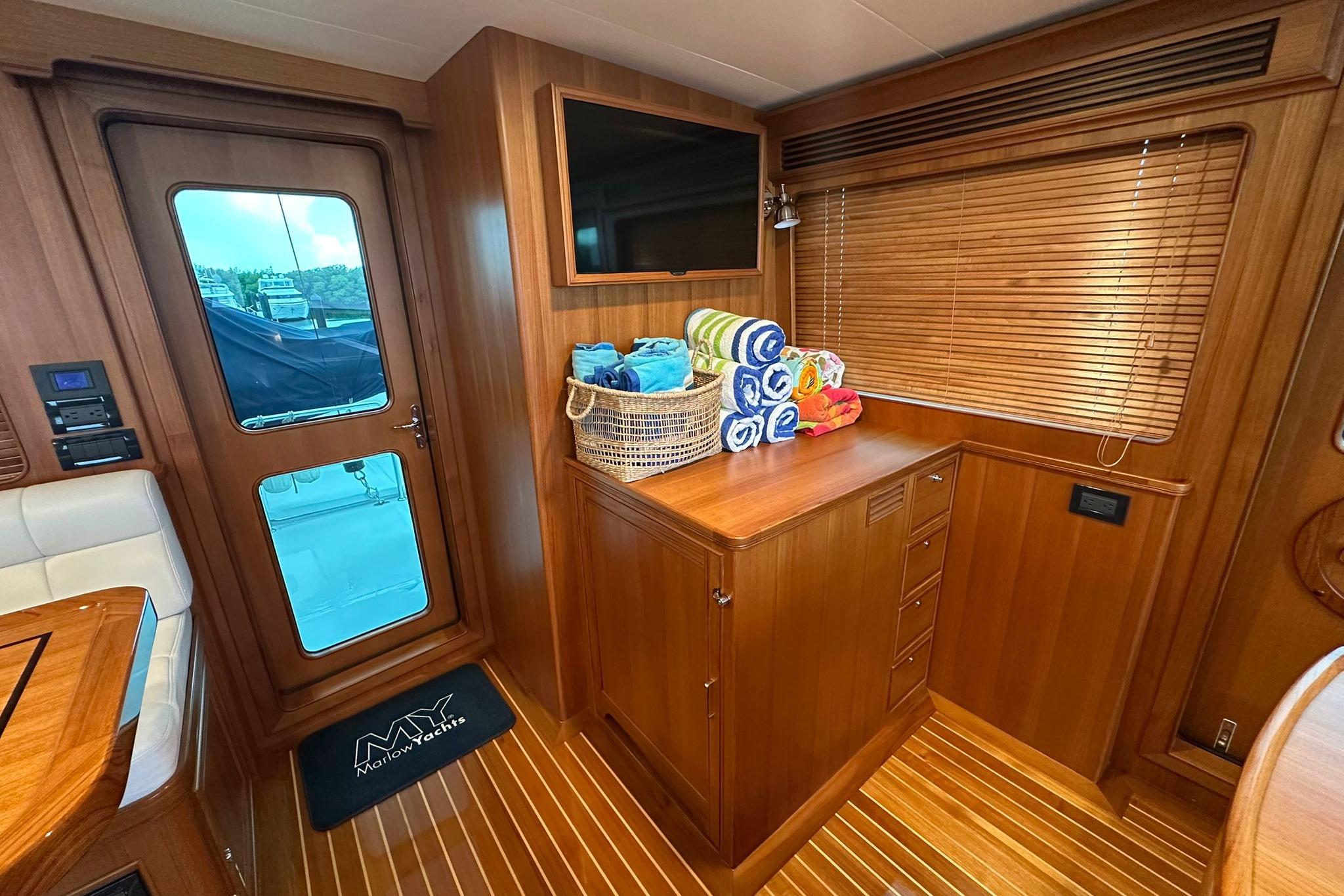 Luxurious interior of 2023 Marlow Explorer 66E-CB yacht with wooden cabinetry and rolled towels.