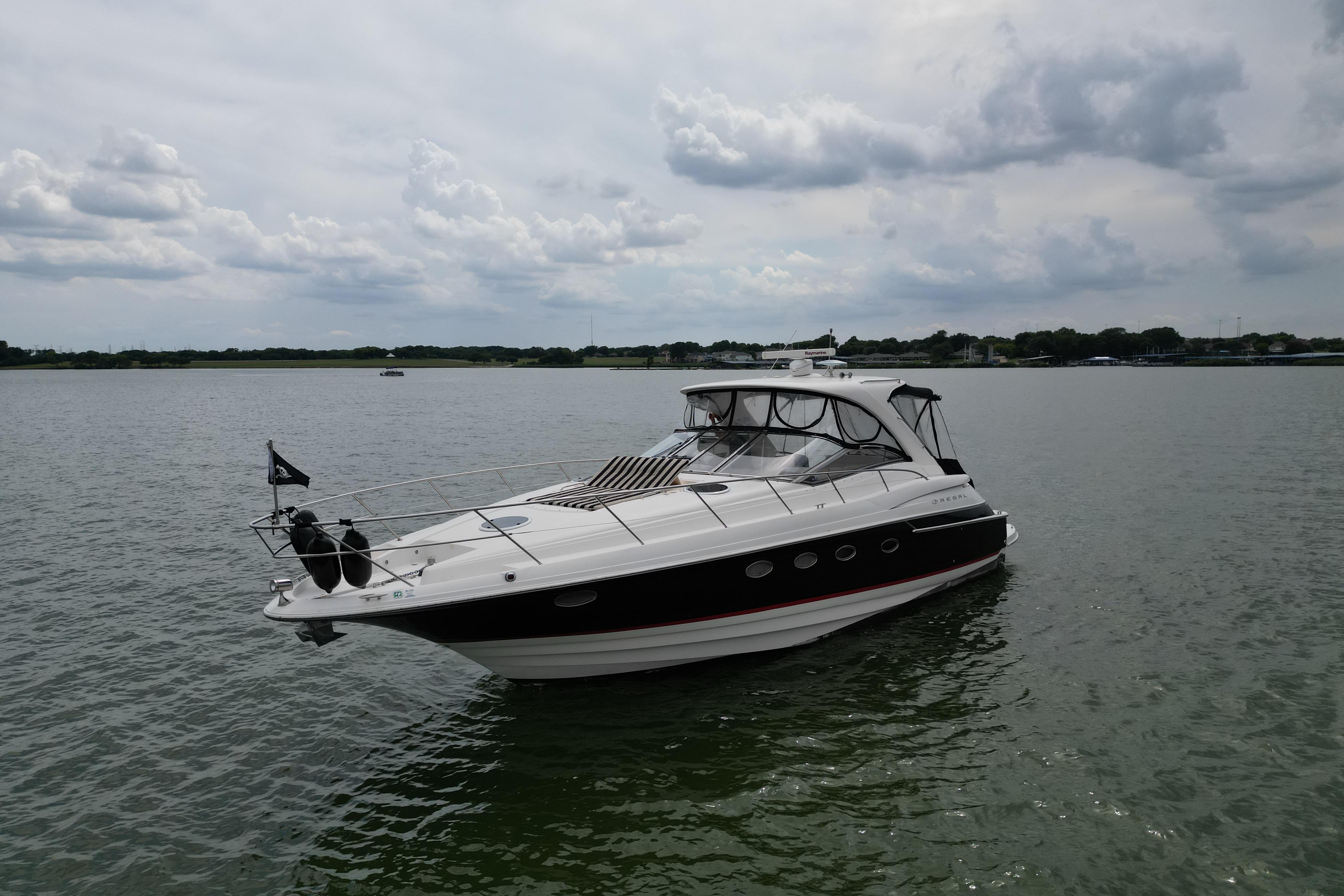 2005 Regal Commodore 4260 yacht on calm water under cloudy sky.
